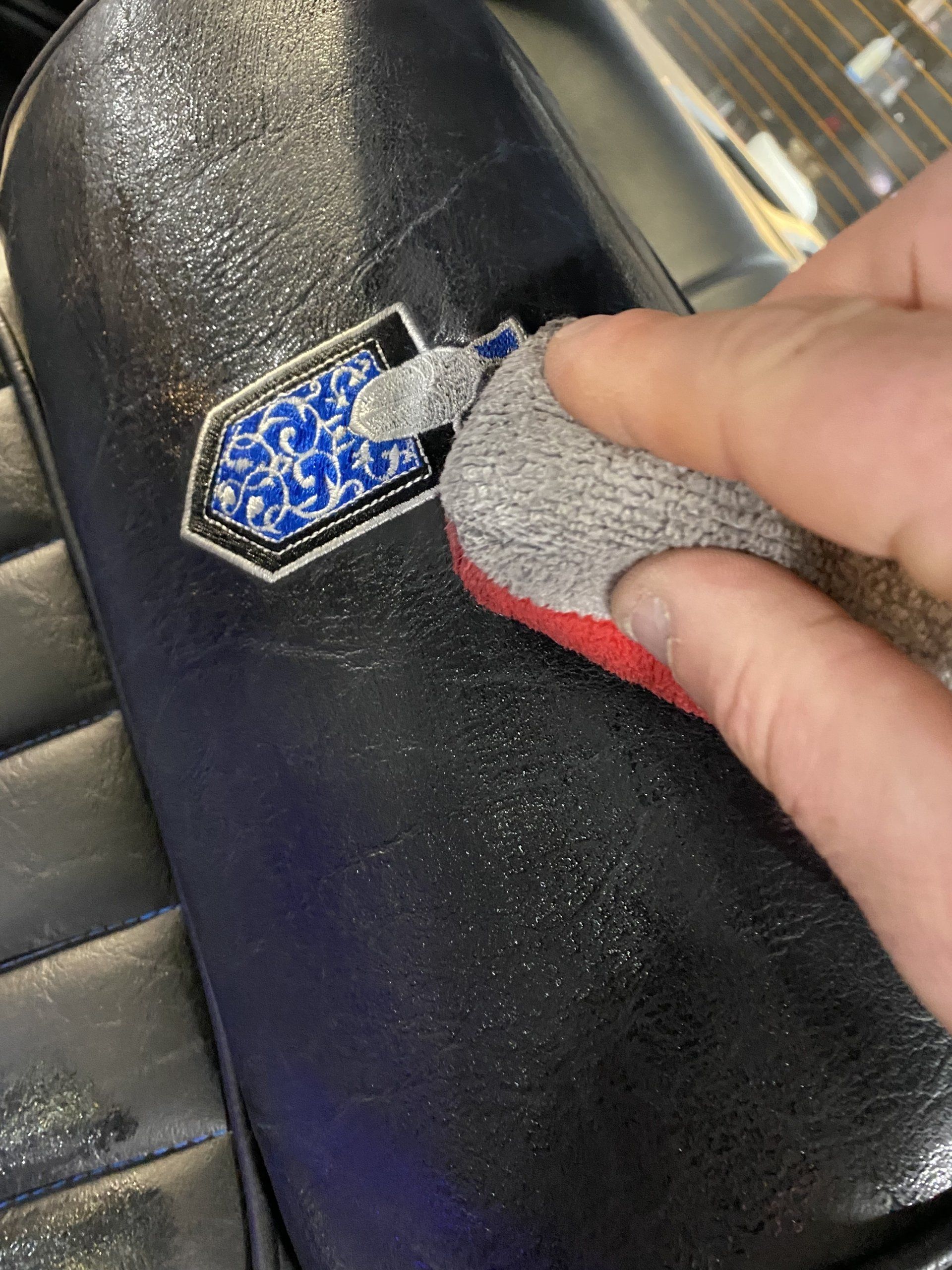 Hand polishing a black leather car seat emblem with a cloth