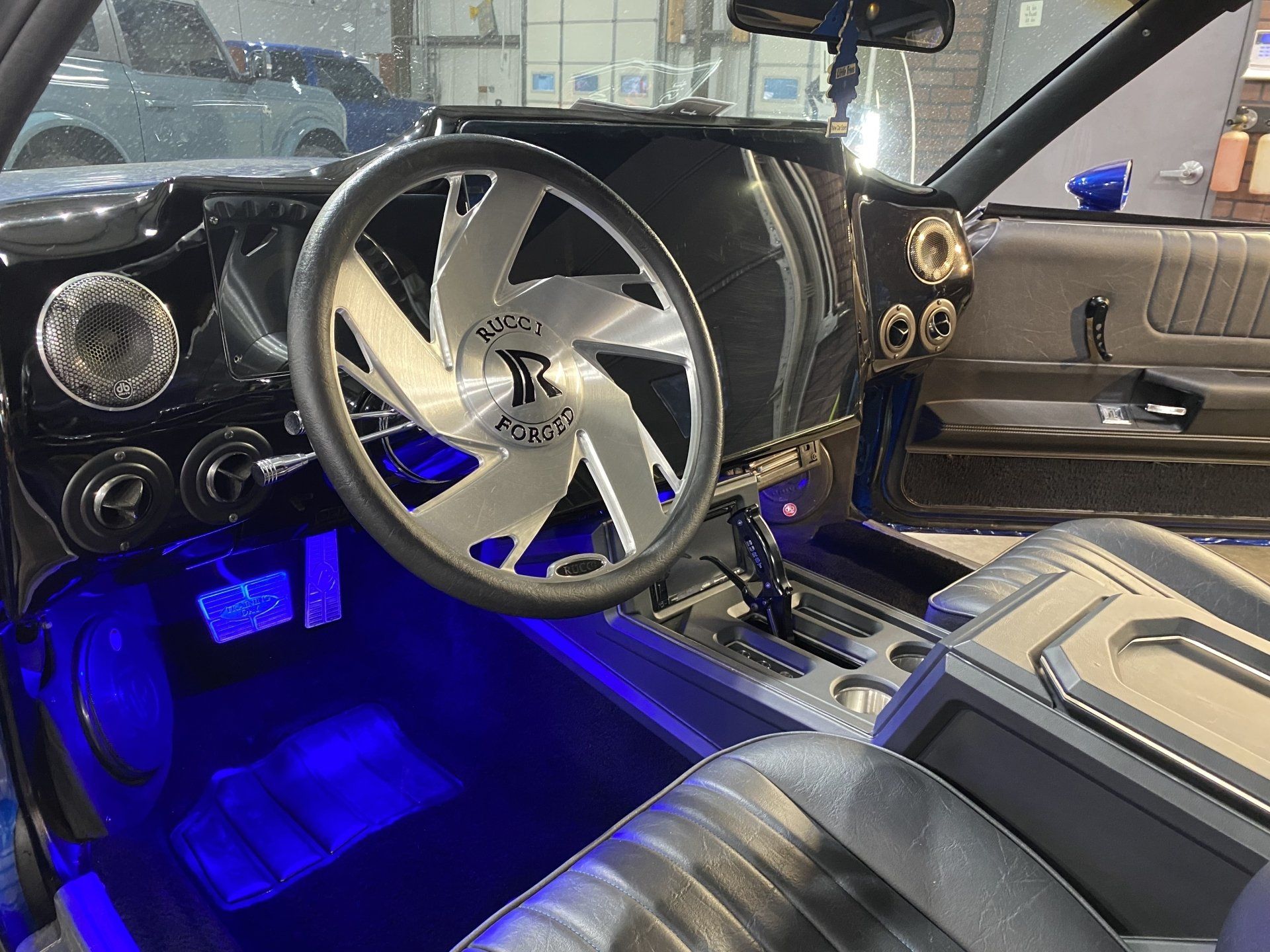 Custom car interior with blue LED floor lighting and a large steering wheel with chrome accents