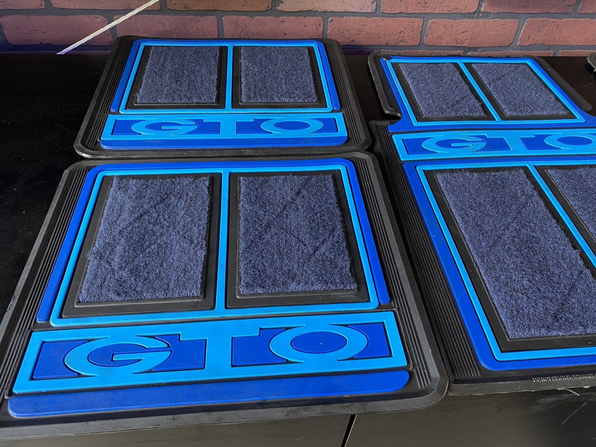 Blue-and-black padded mats stacked on a floor, each with two dark rectangular panels.
