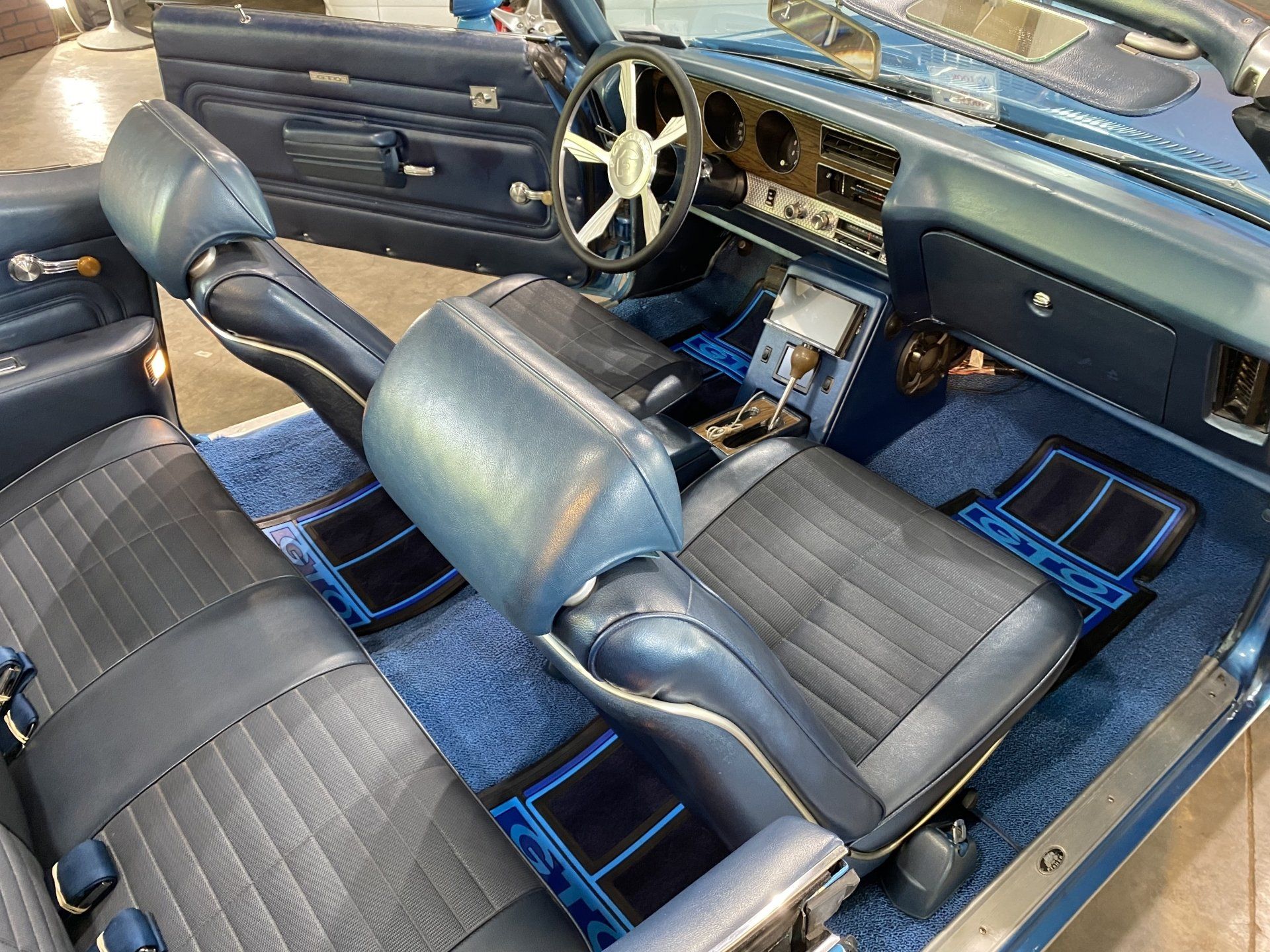 Custom car interior with black and blue seats, sporty steering wheel, and dashboard controls