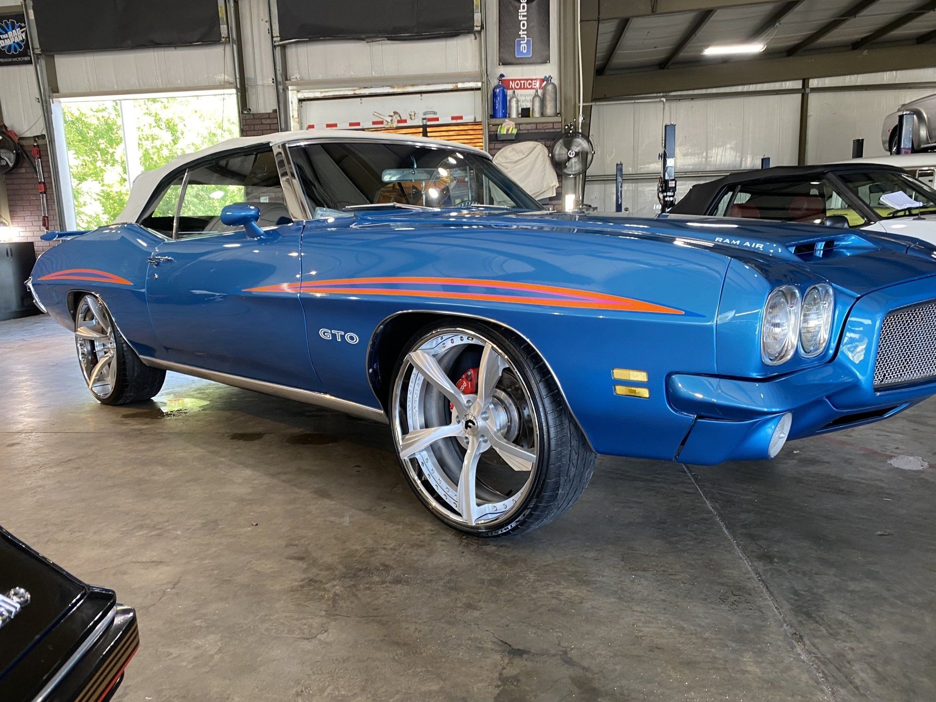 Blue classic muscle car with orange stripes parked inside a garage
