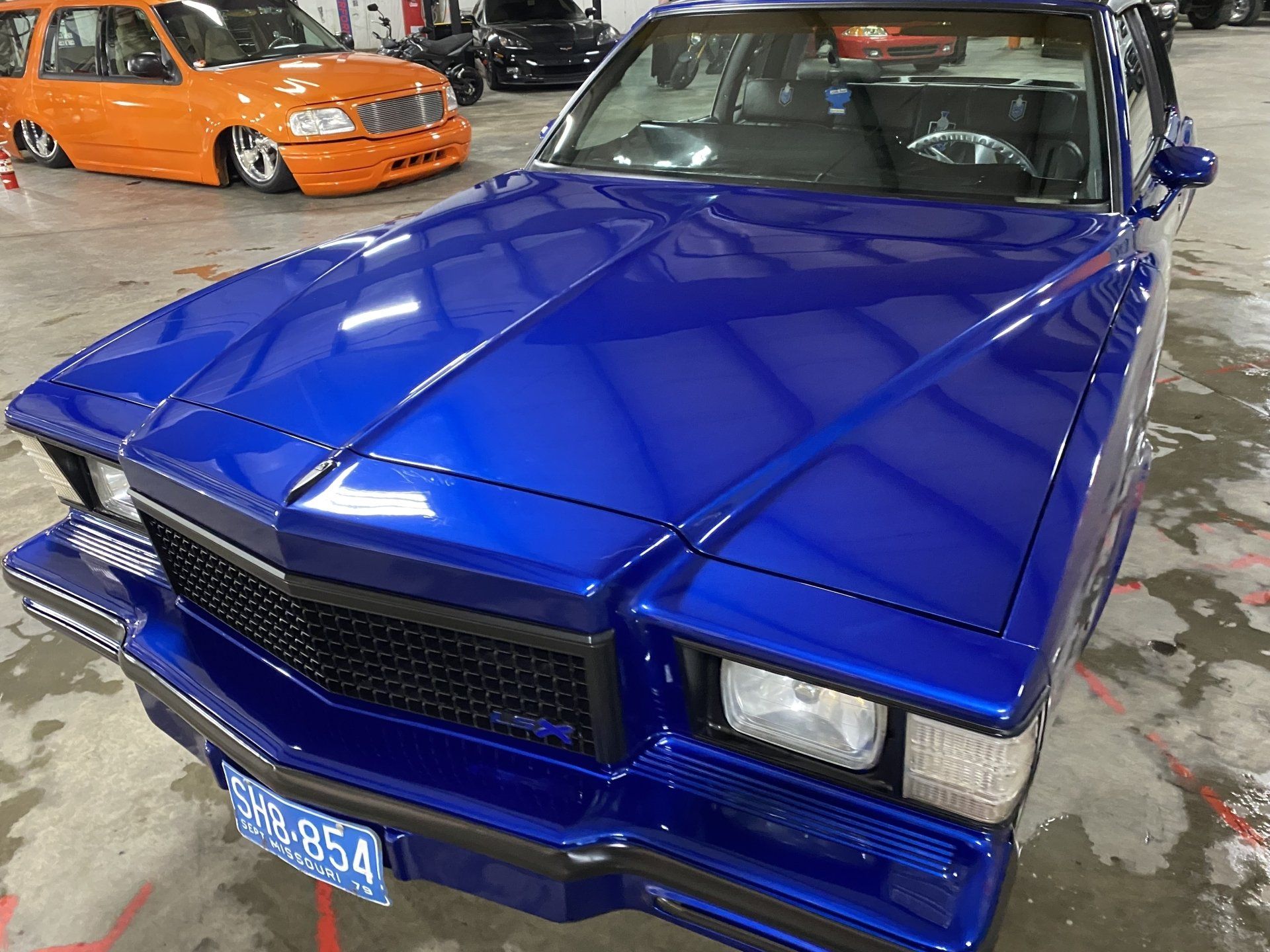 Blue classic car with a custom hood and grille parked indoors at a car show