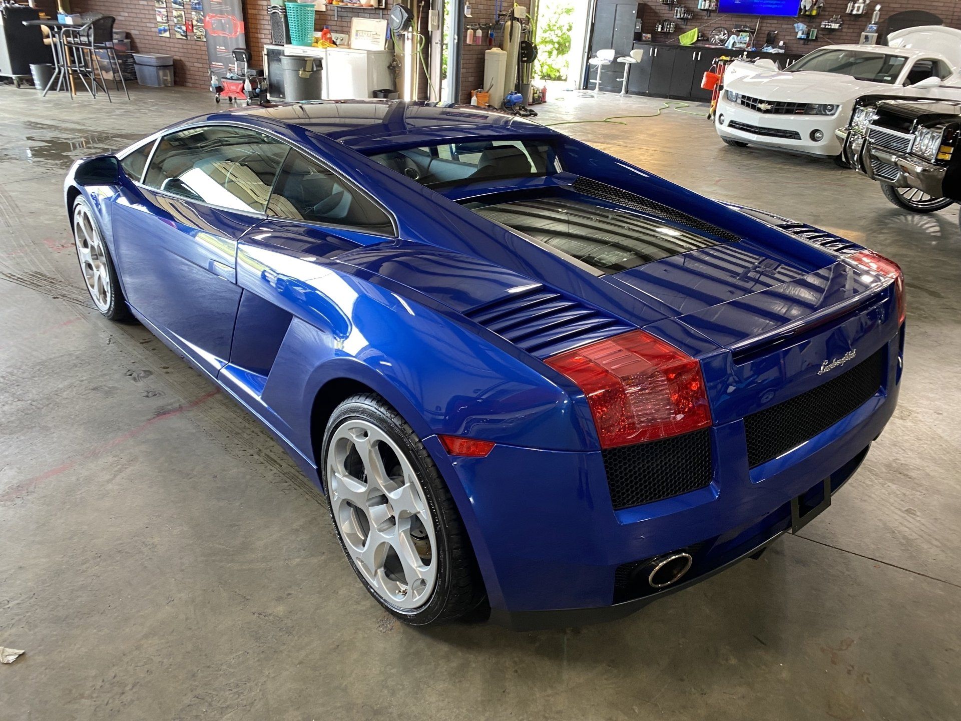 Blue Lamborghini sports car in a garage, rear three-quarter view.