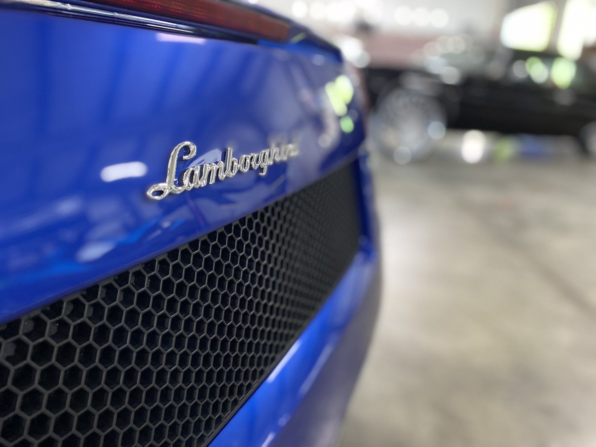 Close-up of a blue Lamborghini badge and grille on a sports car.