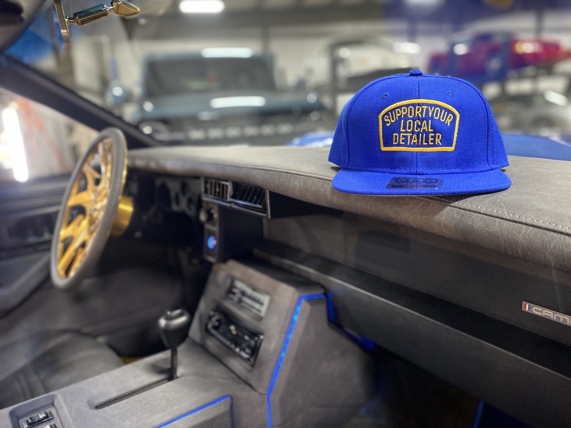 Blue cap on a car dashboard beside a gold steering wheel in a dark interior