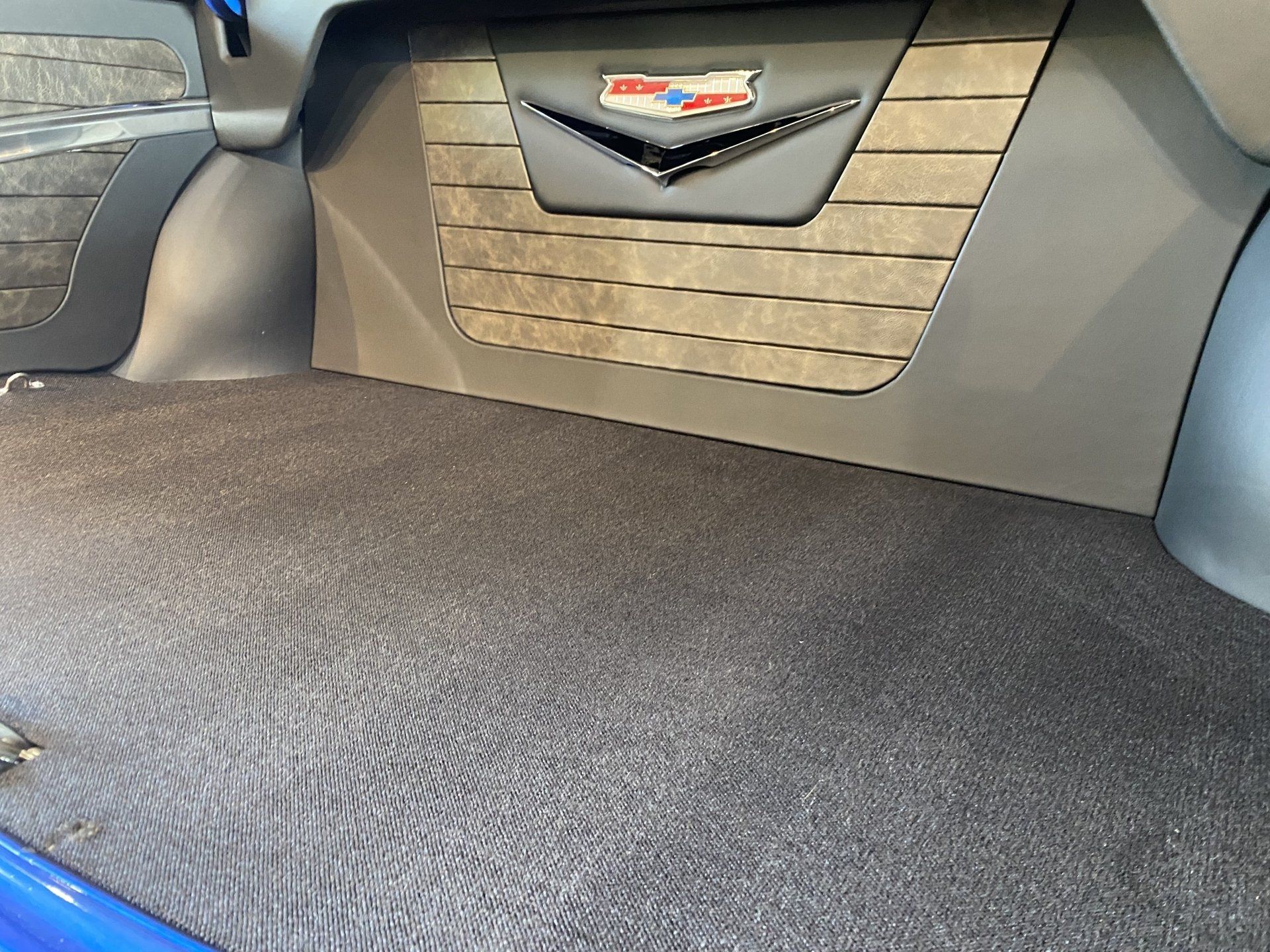 Car trunk interior with dark carpeted cargo floor and Cadillac emblem on the back panel