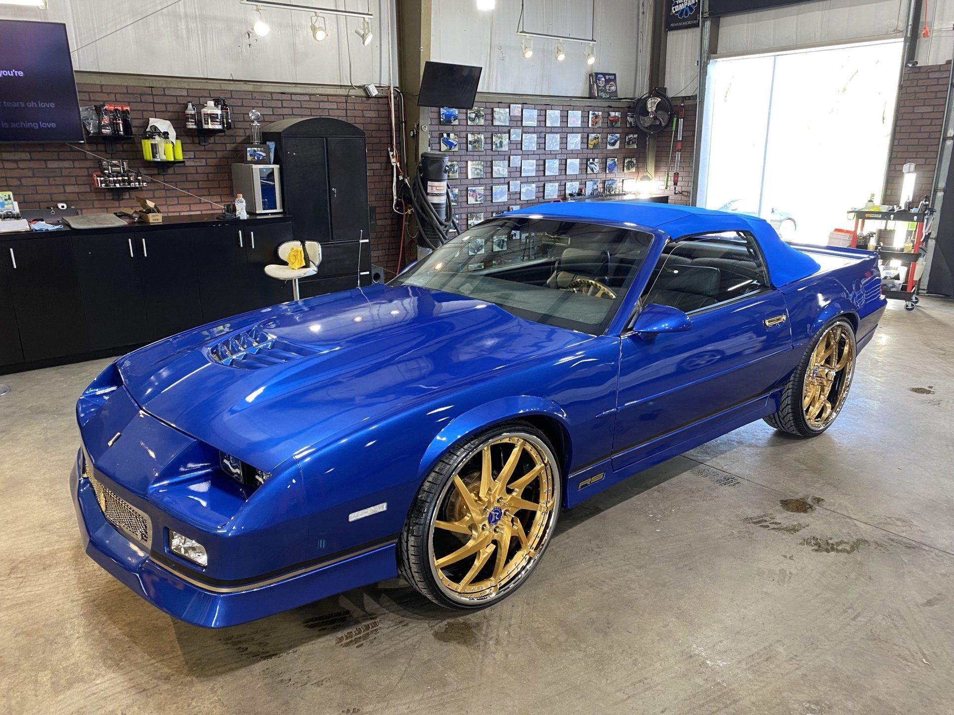Blue sports car with gold rims parked in a garage.