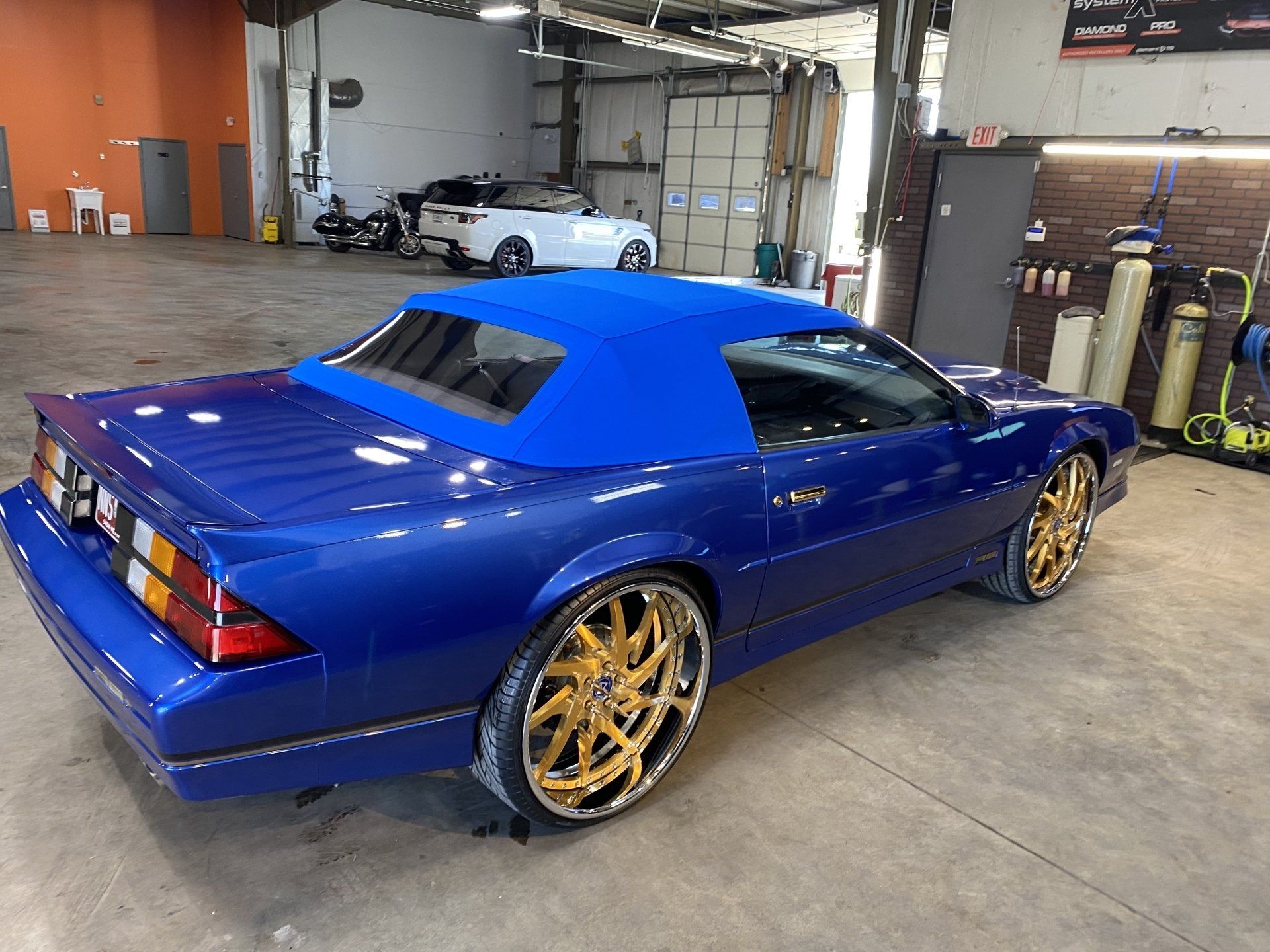 Blue sports car with gold rims parked in a garage
