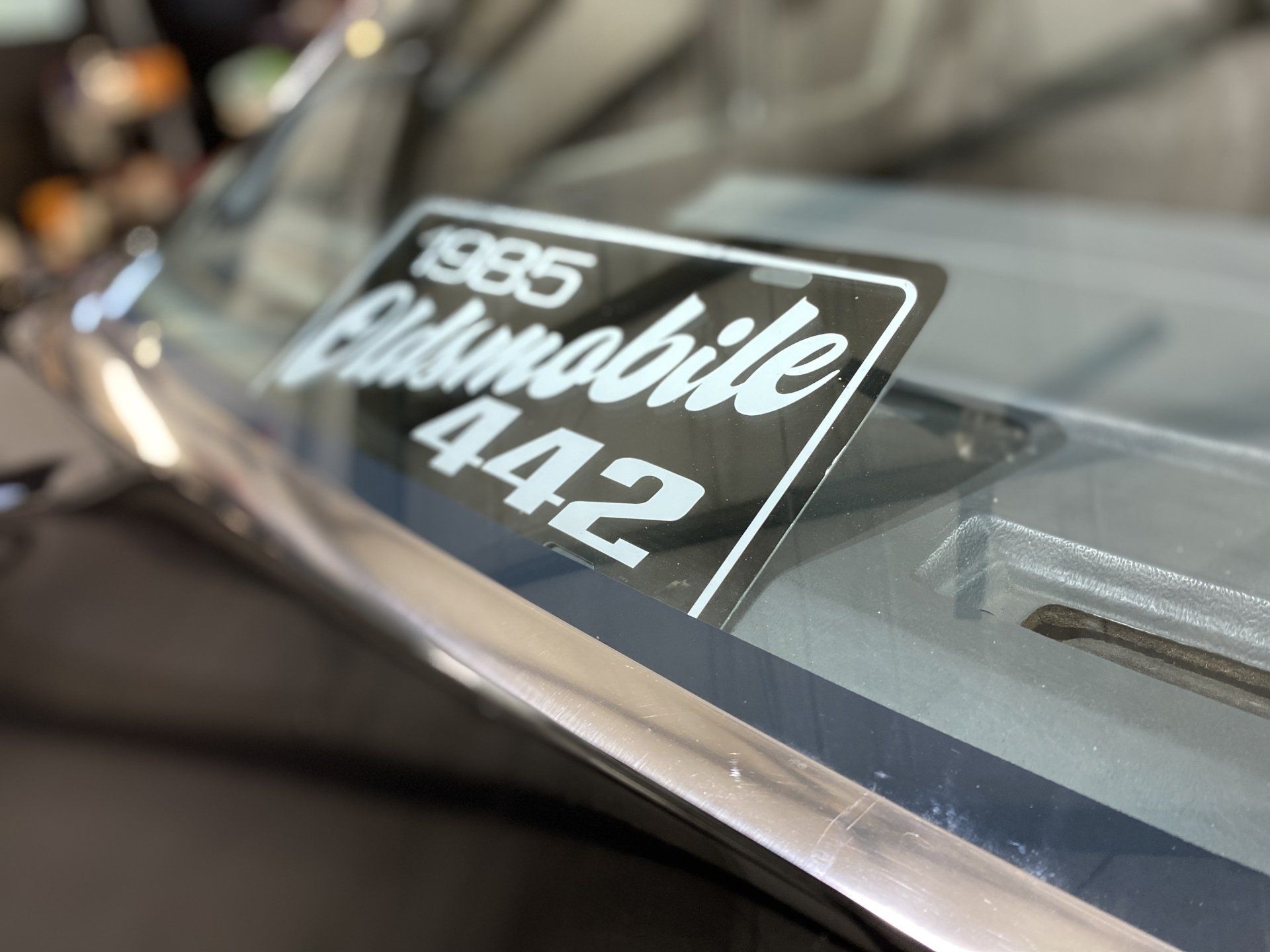 Close-up of a vintage Chevrolet badge with “442” on a reflective car surface