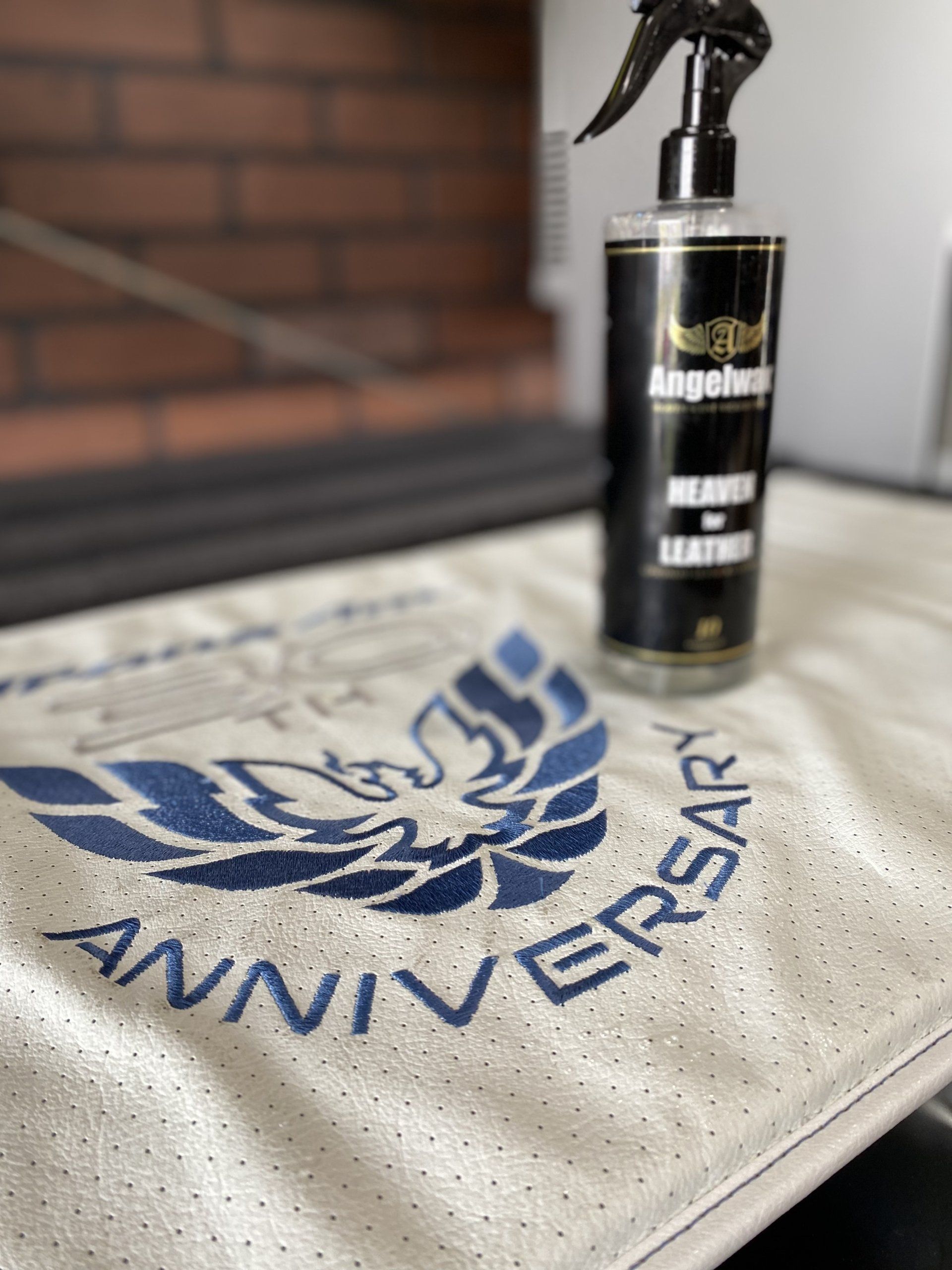 White anniversary towel with blue eagle logo and spray bottle on a table by a fireplace