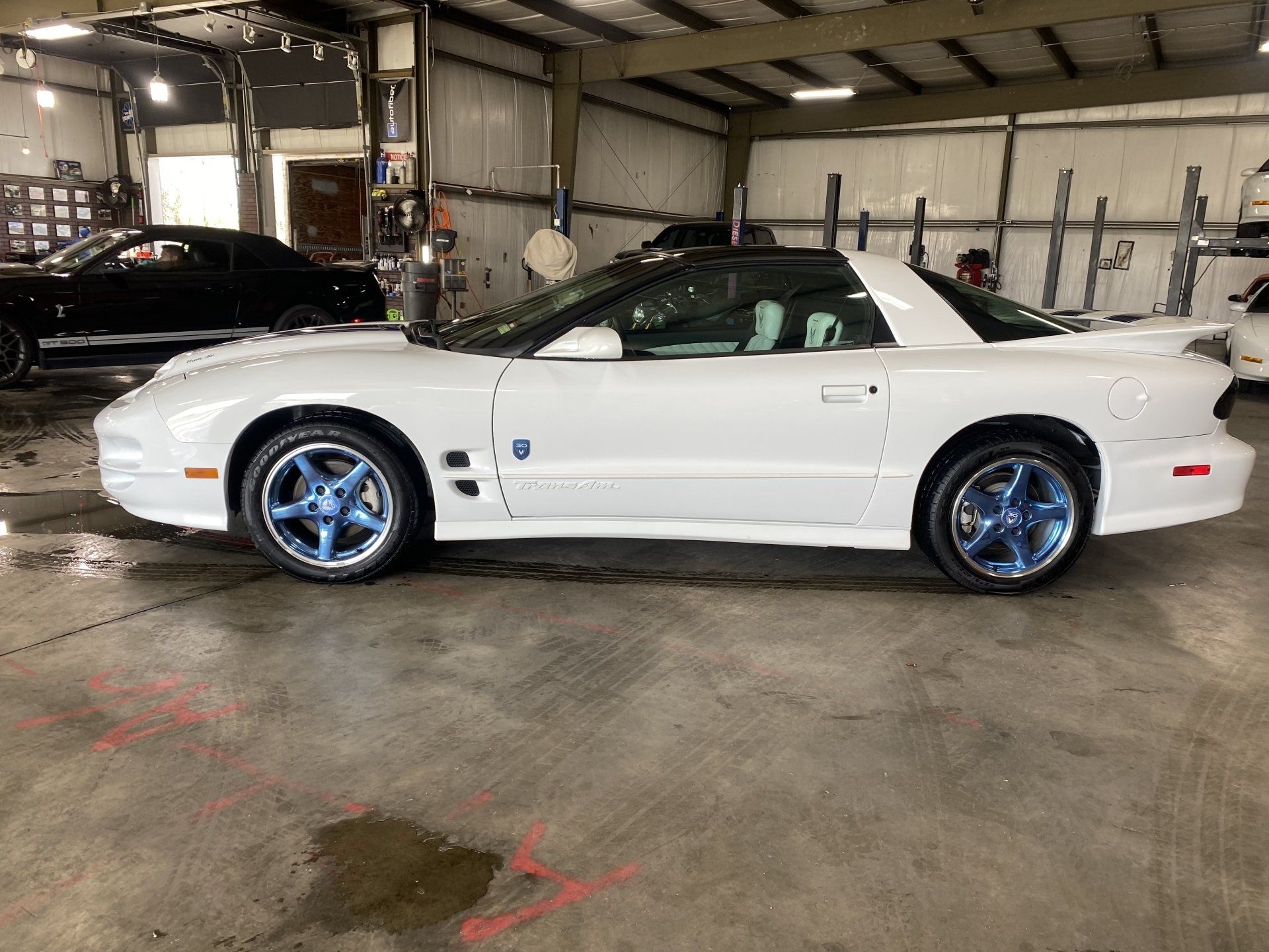 White convertible sports car with blue rims parked in a garage
