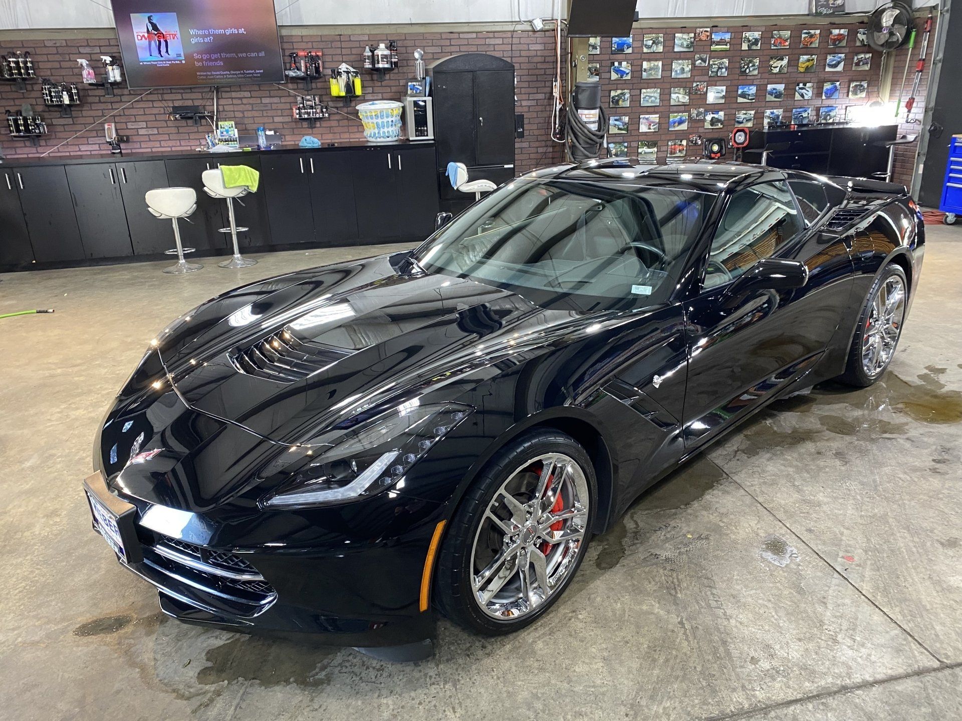 Black sports coupe in a garage, with polished floor and workbench in the background