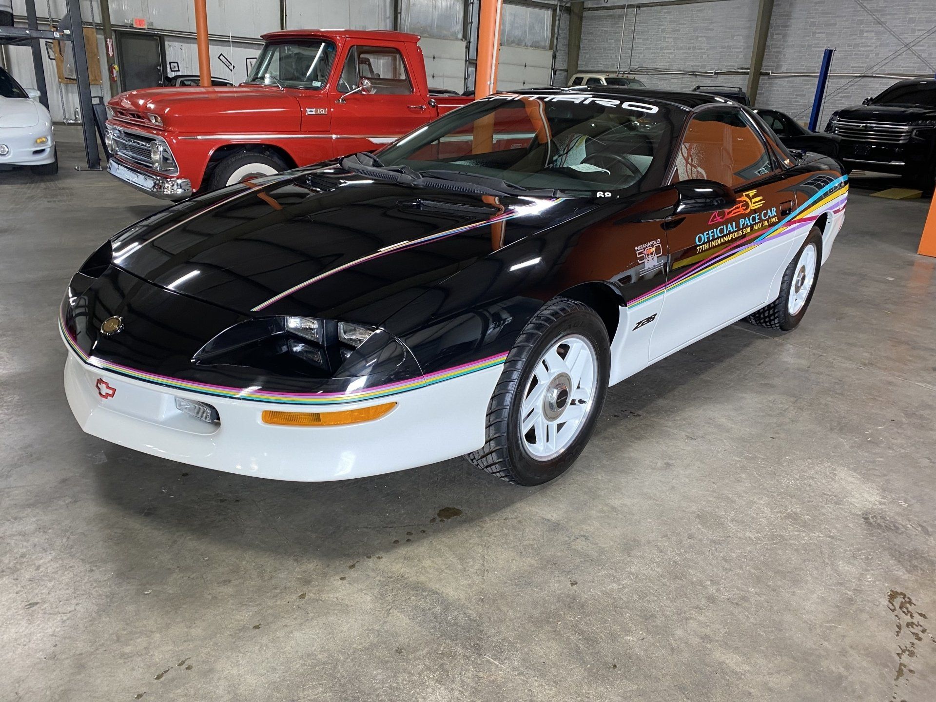Black and white sports car with red and gold racing stripes parked indoors in a garage