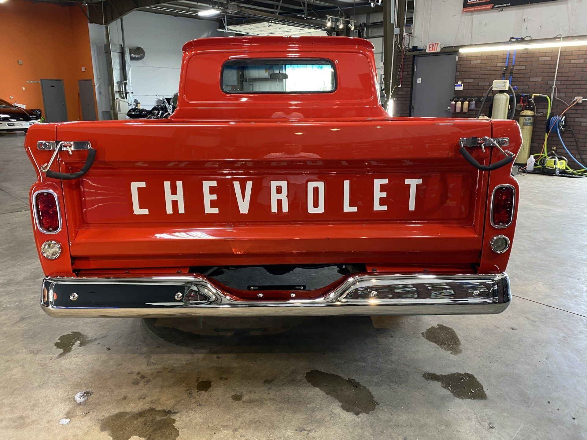 Rear view of a red Chevrolet pickup truck in a garage, with chrome bumper and tailgate lettering.