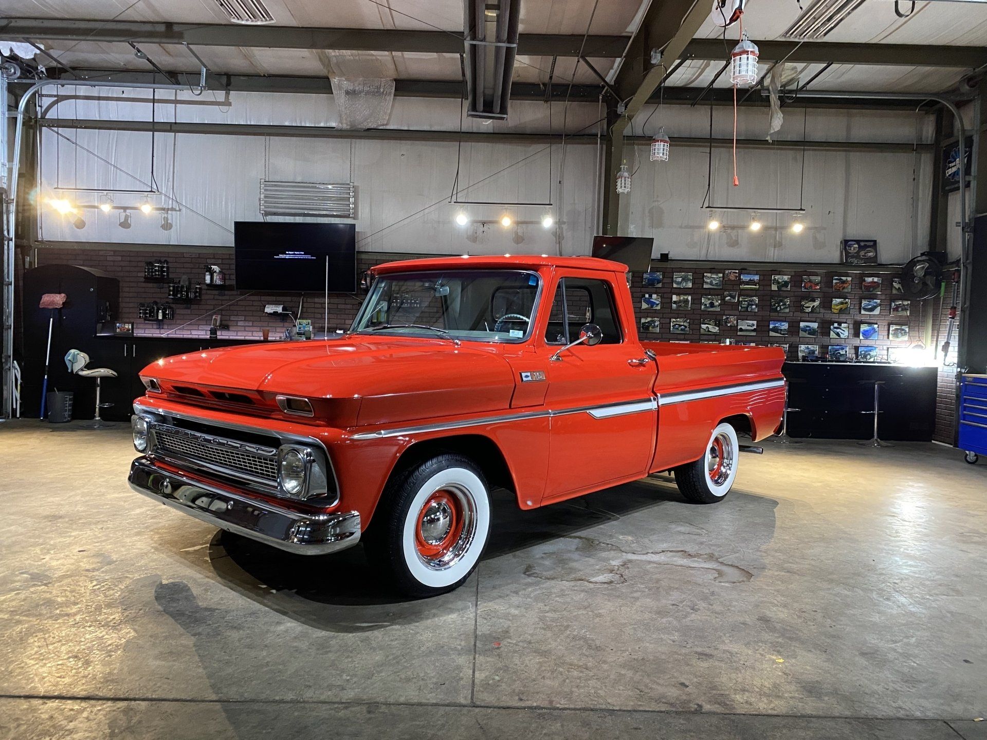 Red classic pickup truck in a garage, glossy finish, with chrome grille and whitewall tires