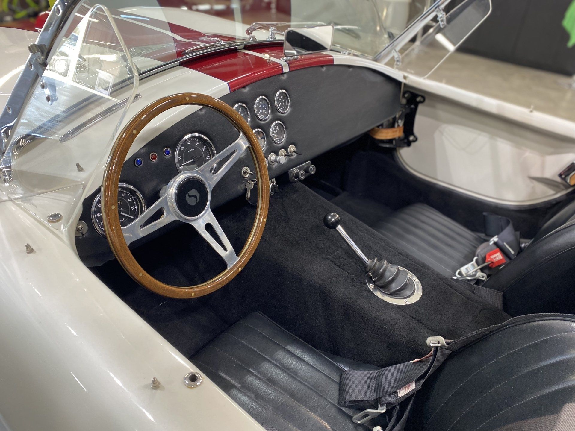 Vintage car interior with tan steering wheel, black seats, and manual gear shift