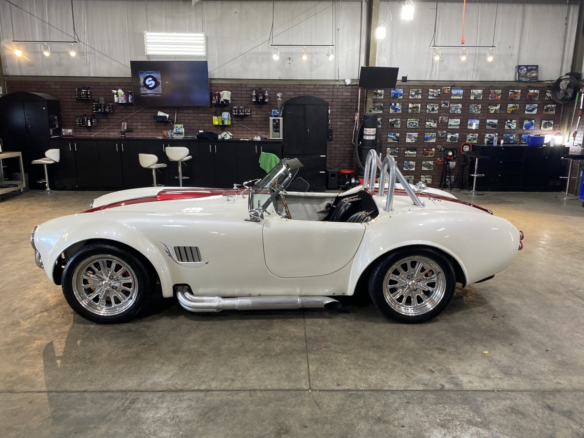 White classic convertible sports car in a garage, with racing stripes and tools in the background