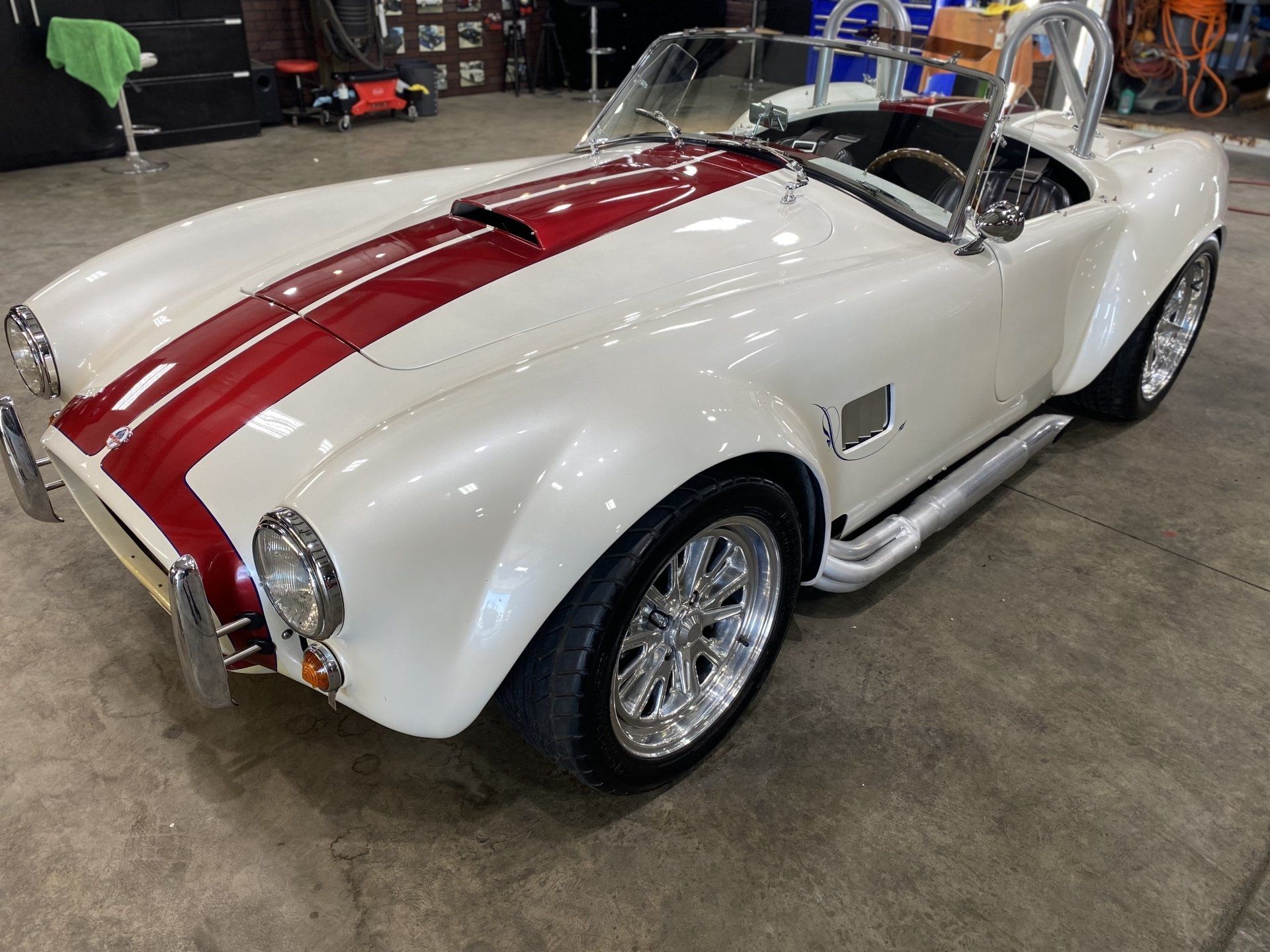 Red and white classic convertible sports car with racing stripes displayed indoors