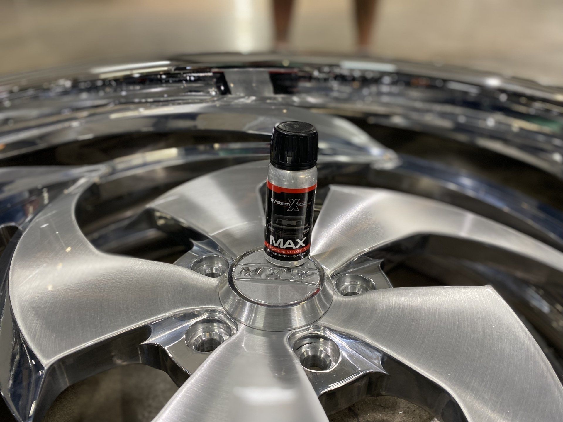 Close-up of a chrome car wheel rim with a small black-and-red can standing in the center hub.