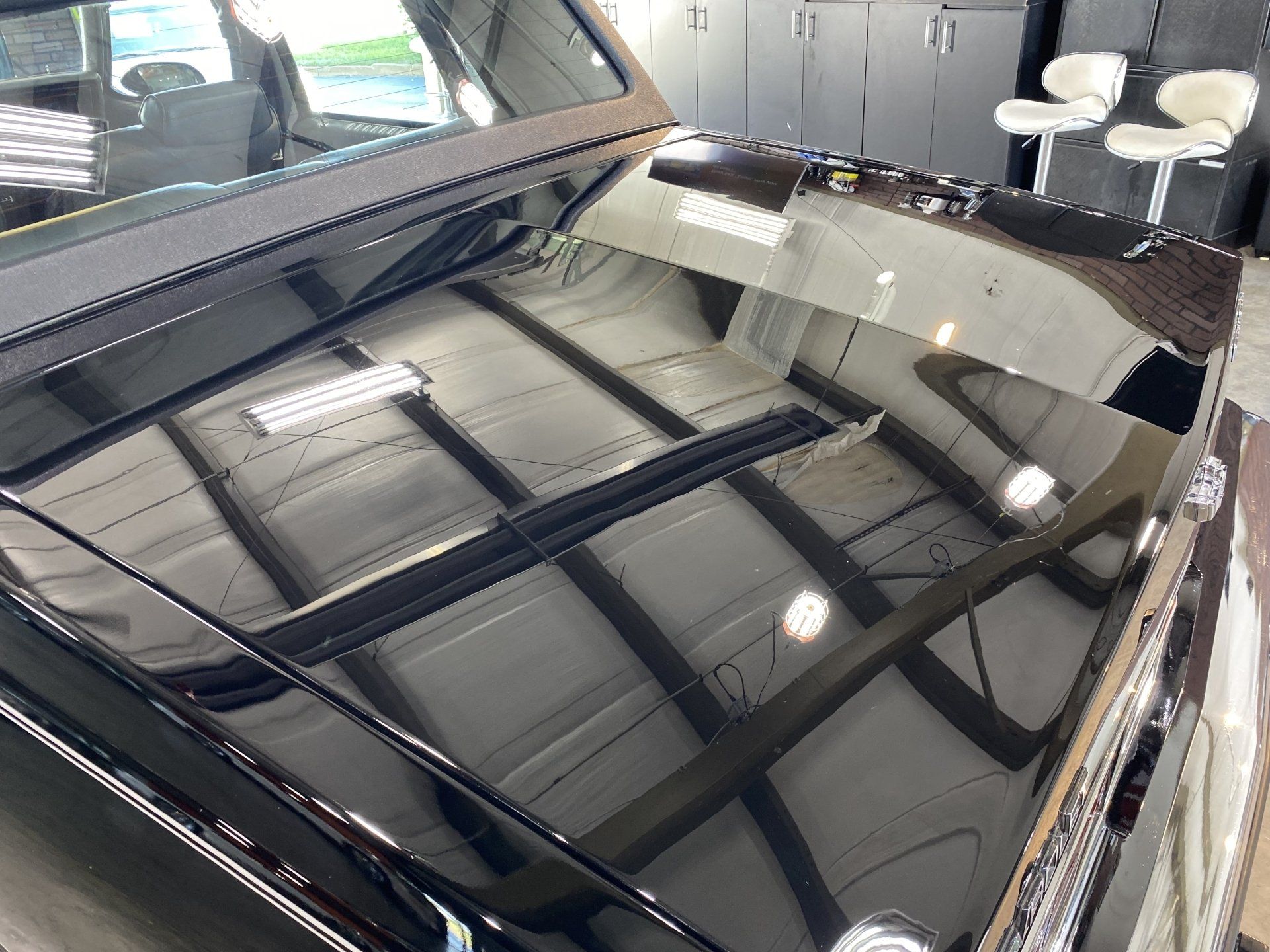Glossy black car roof with reflections inside a garage or showroom