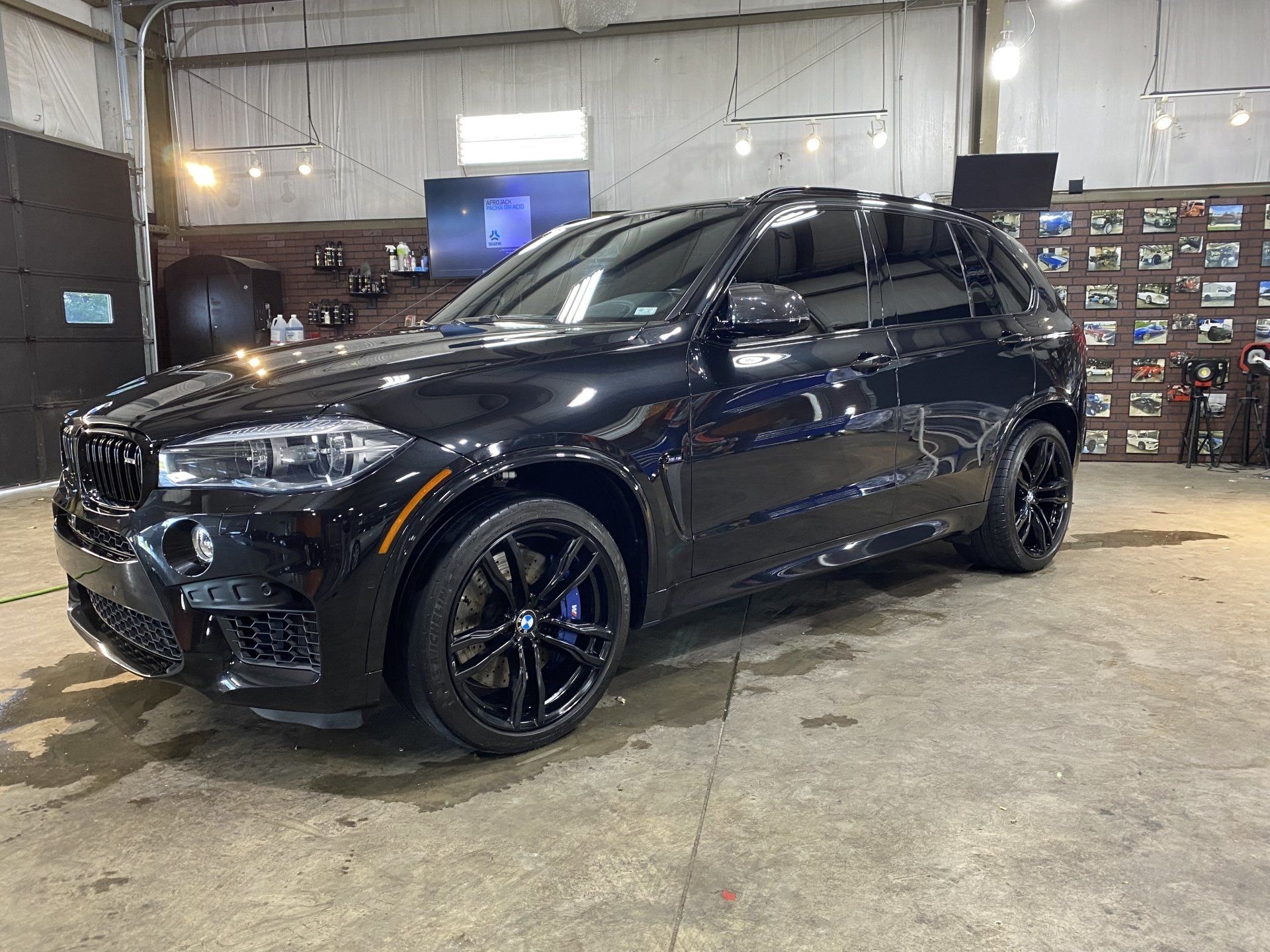 Black SUV parked inside an auto shop, viewed from the front-left side.