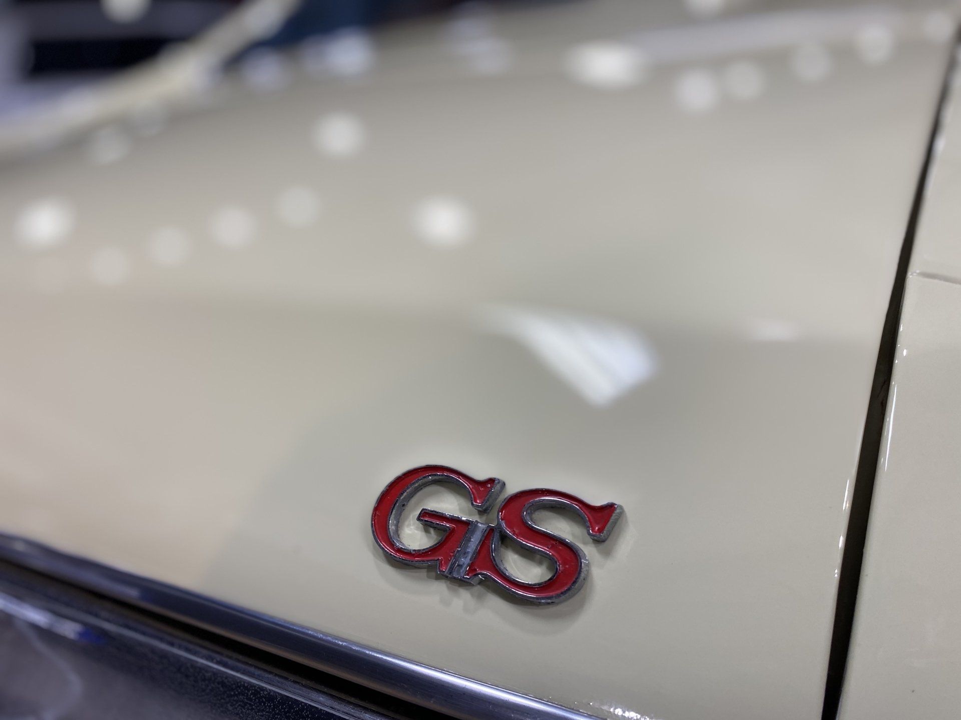 Close-up of a white car’s red and chrome GTS badge on the rear panel
