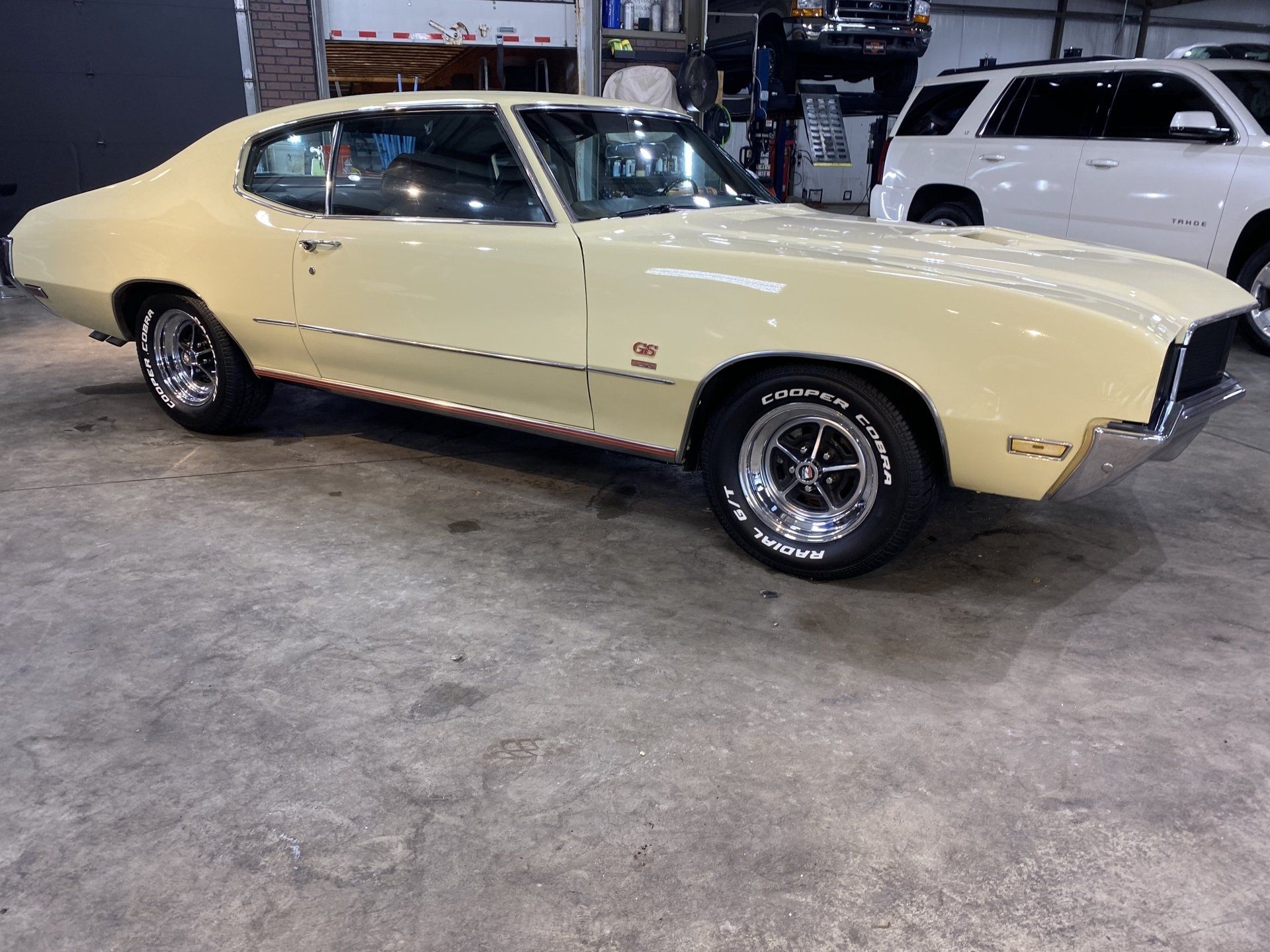 Classic cream-colored muscle car parked indoors at a car show