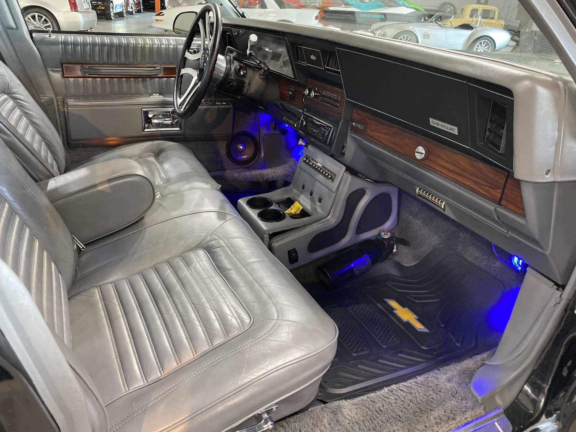 Custom car interior with gray leather seats, wood trim, and blue LED accent lights
