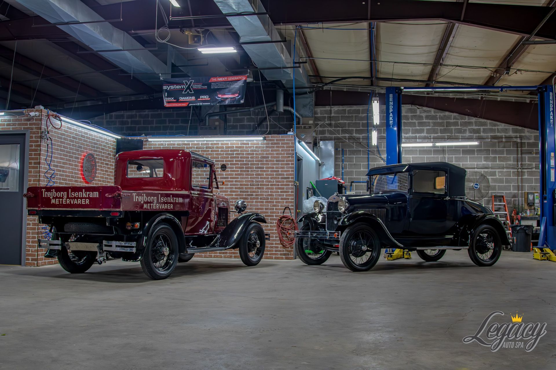 Two vintage trucks, one red and one black, parked inside an industrial garage