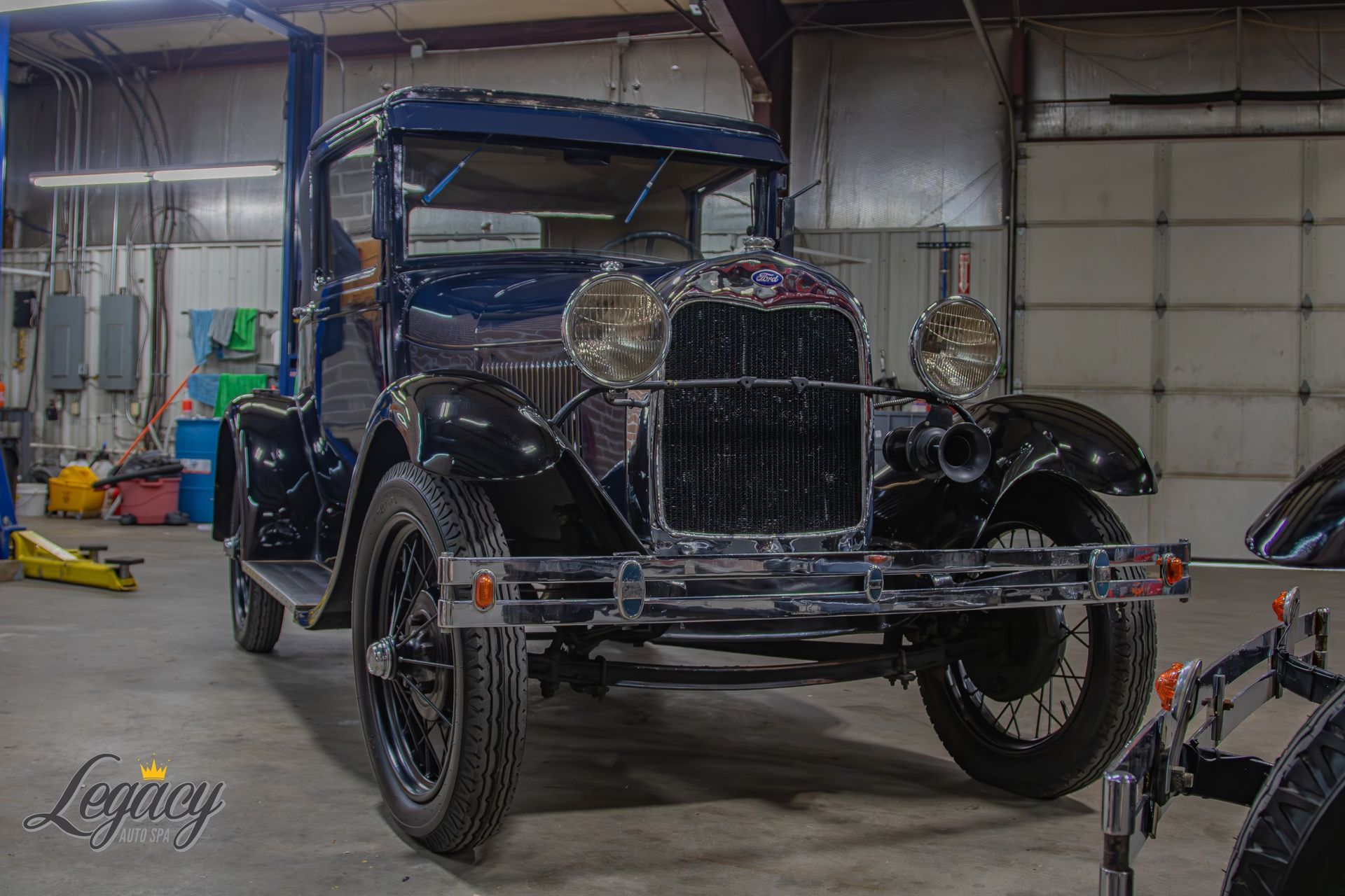 Vintage black antique car in a garage, front view with chrome details and a tow strap attached to the bumper