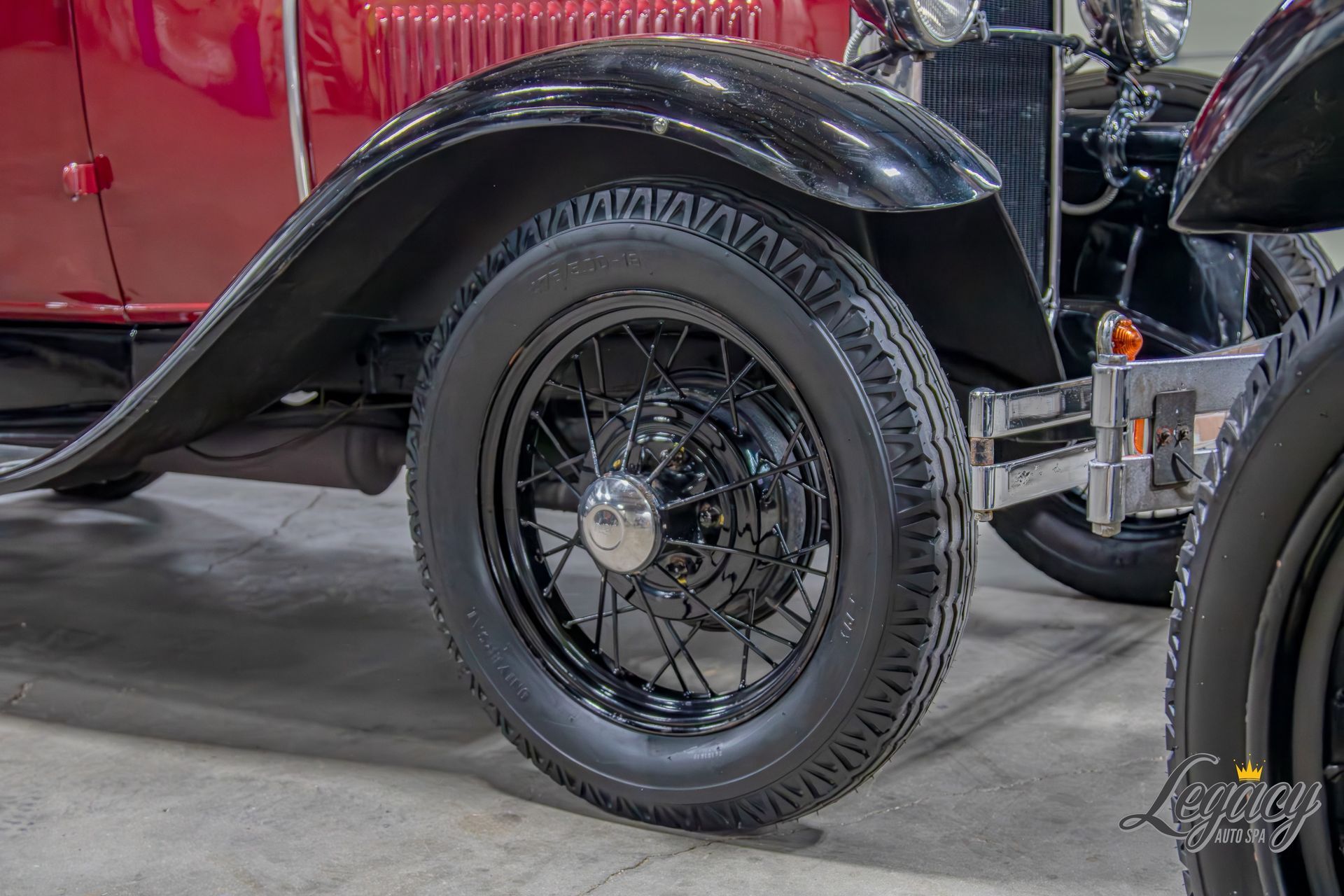 Close-up of a black vintage car’s rear wheel and fender in an indoor showroom