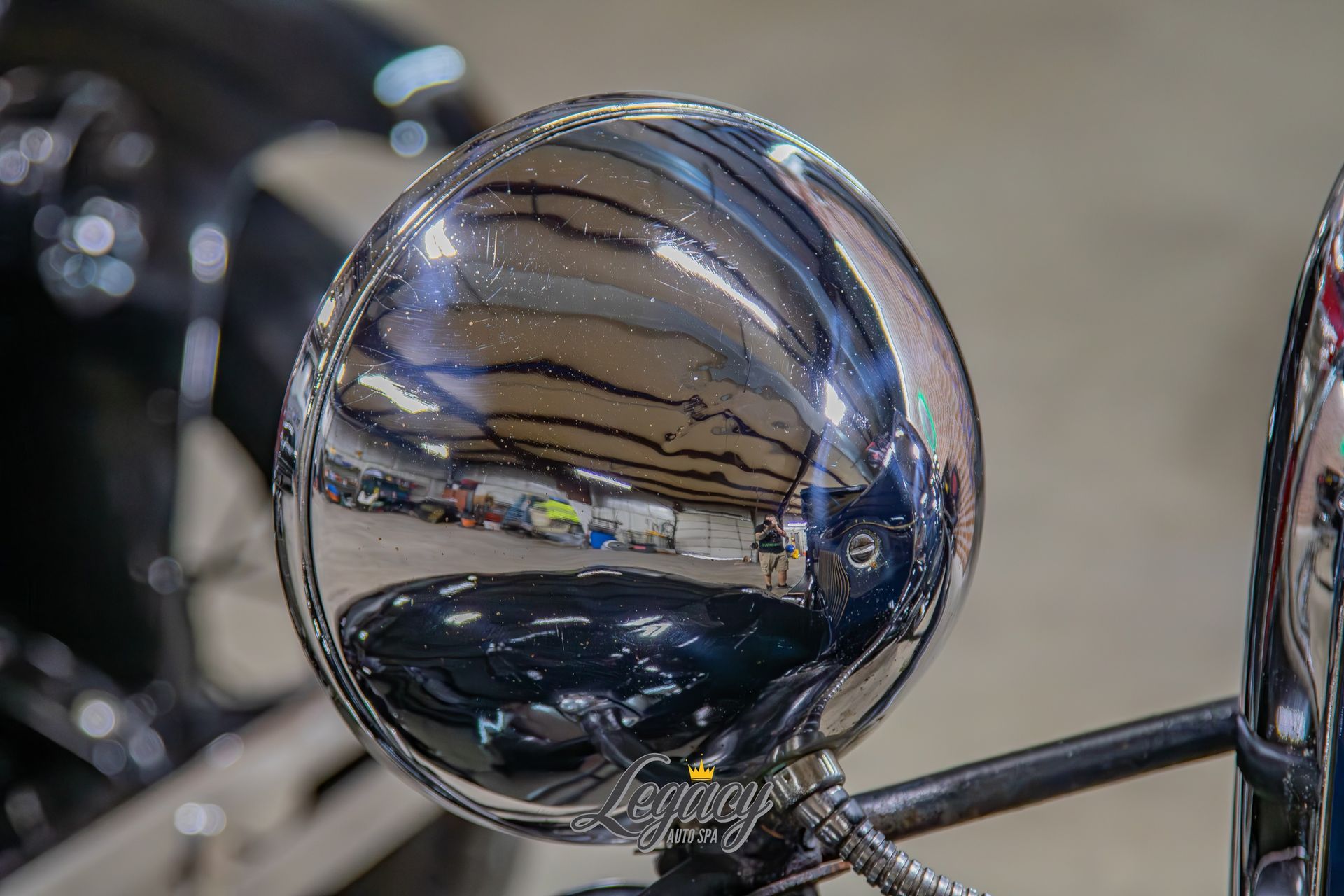 Close-up of a chrome motorcycle mirror reflecting the street and nearby bikes.