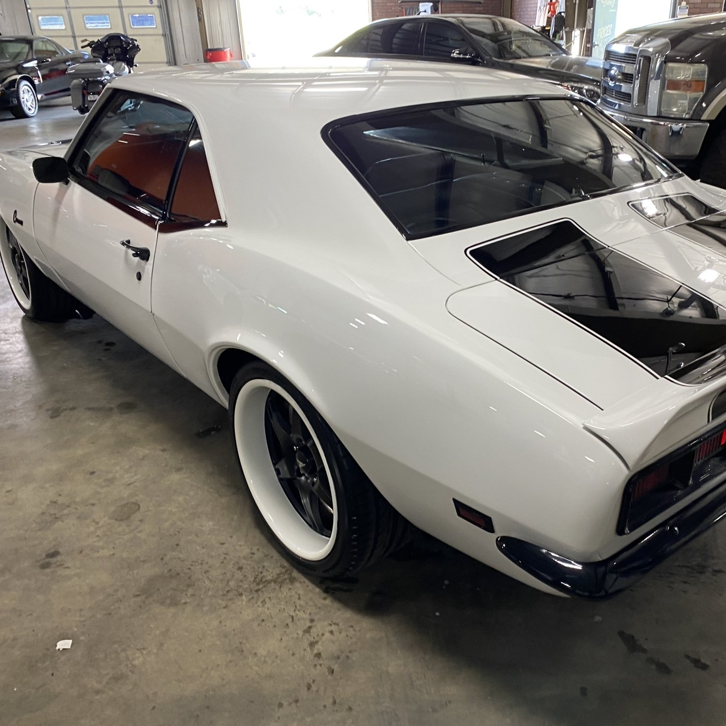 White classic muscle car with exposed rear engine, parked indoors in a garage