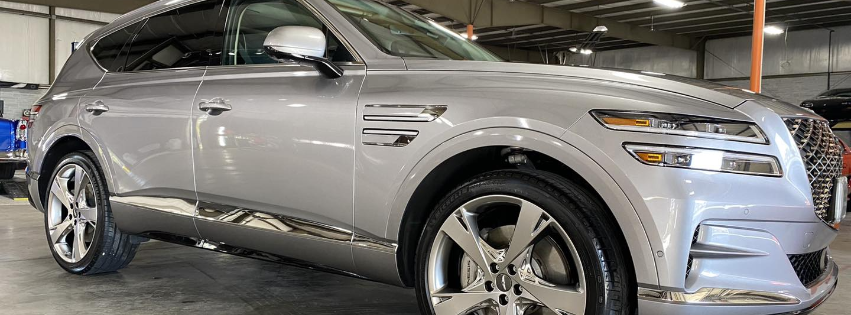 Silver luxury SUV parked indoors, front three-quarter view with chrome accents and large alloy wheels