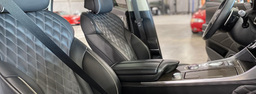 Black leather car seats and center console in a showroom, with a blue quilted seat cover in the foreground