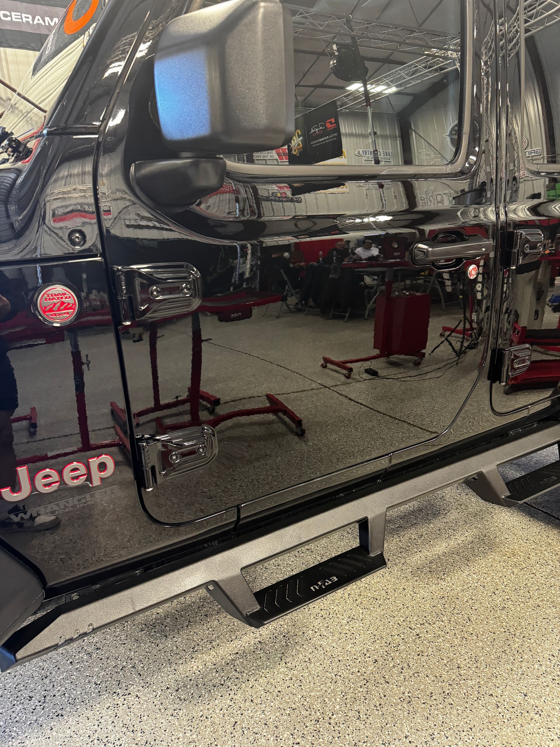 Black Jeep door with a glossy reflection of a garage and lift equipment