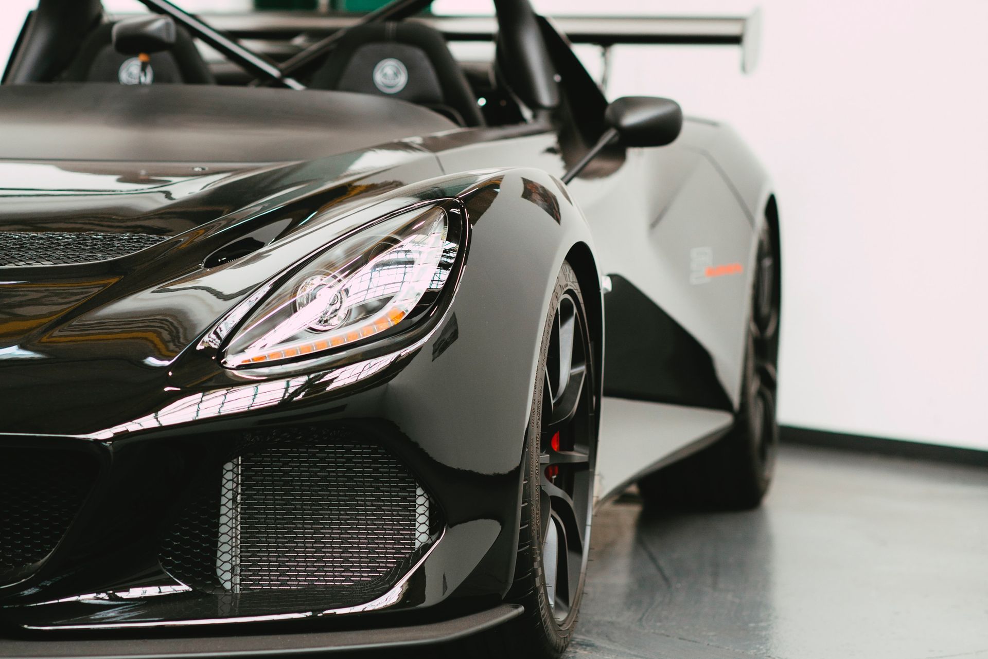 Black sports car in a showroom, front-left view with glossy body and sleek headlights