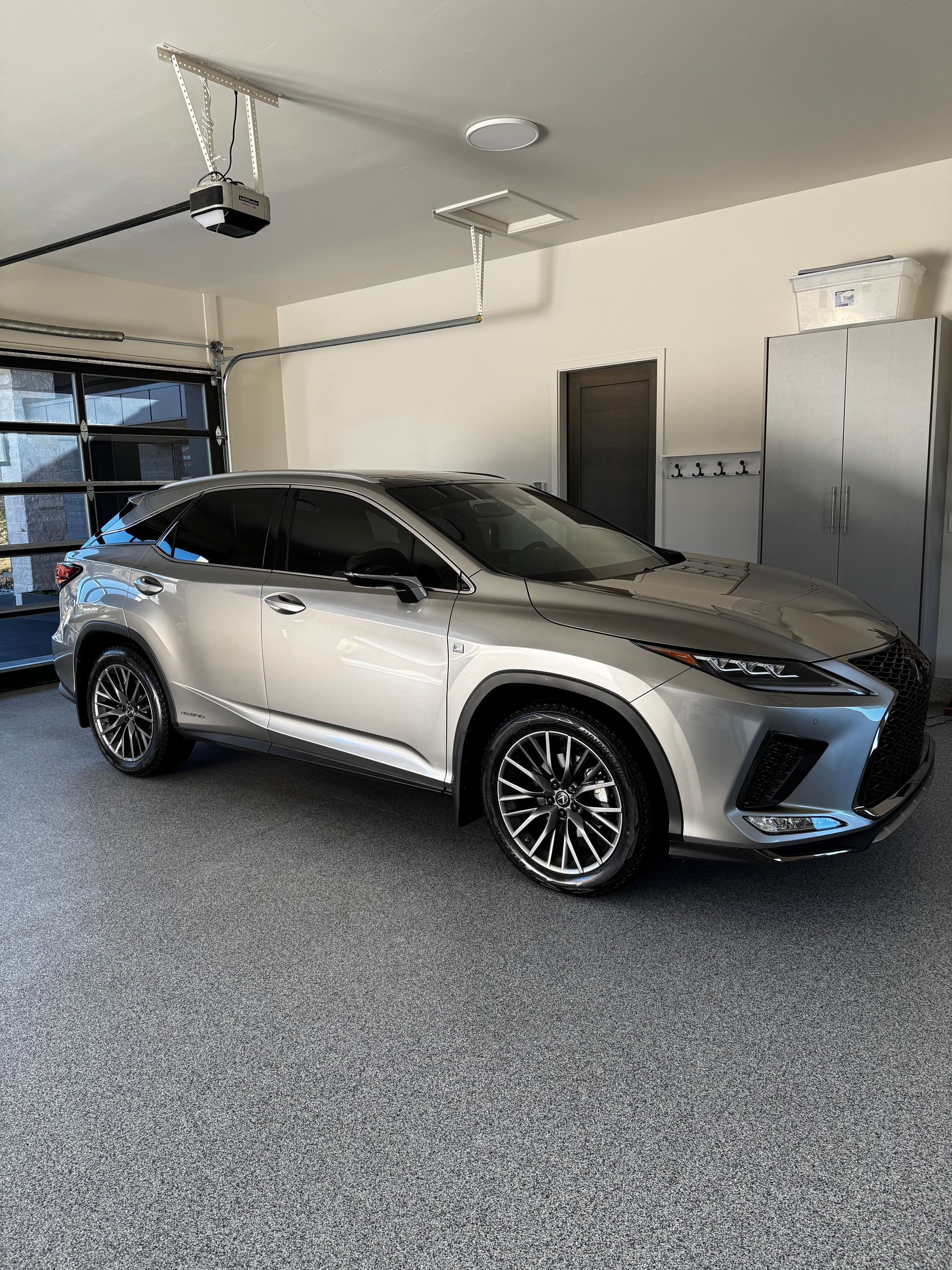 Silver SUV parked inside a garage with gray cabinets and a speckled floor.