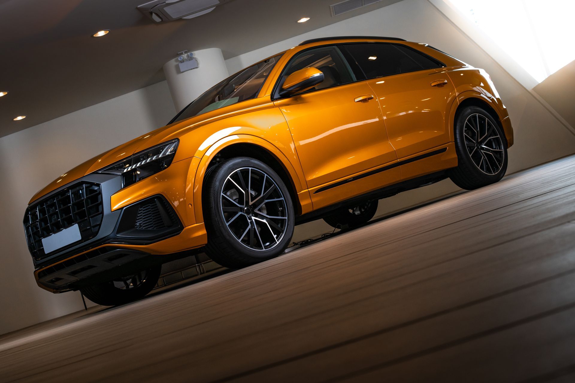 Orange sports SUV on a showroom floor, angled view under bright lights