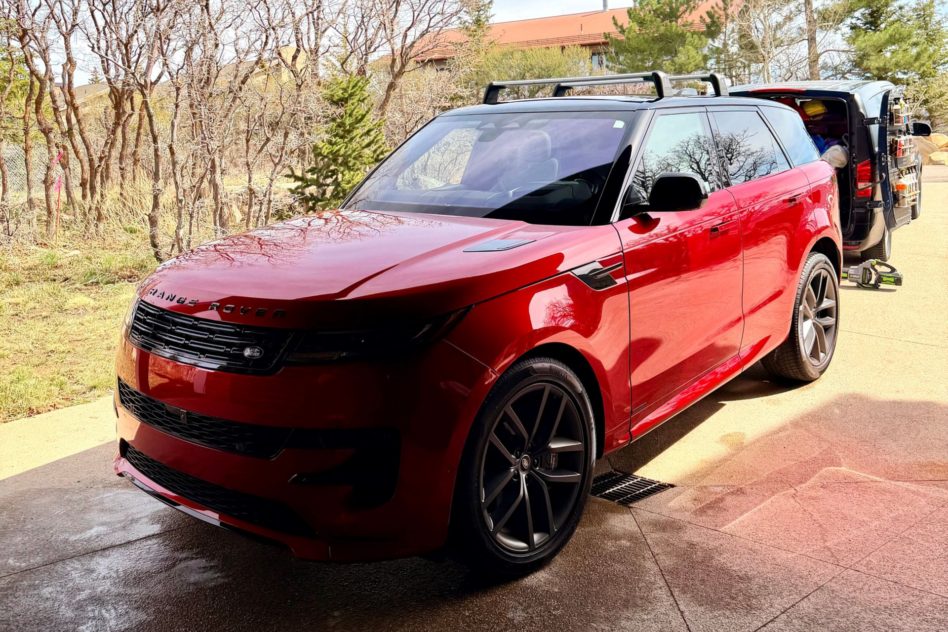 Red SUV parked on a driveway with a rear bike rack, in bright sunlight