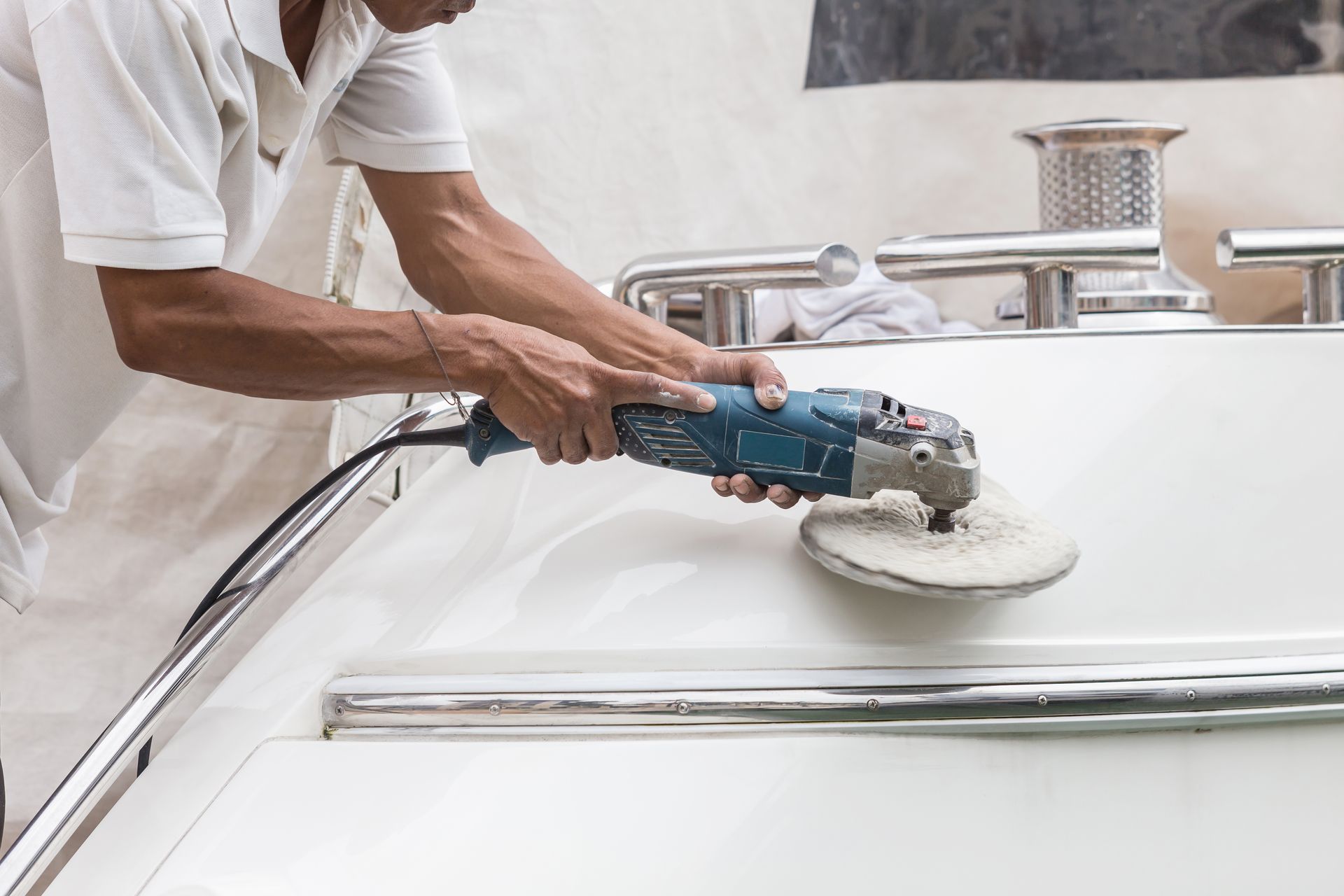 Person using a blue buffer to polish a white bathtub in a bathroom