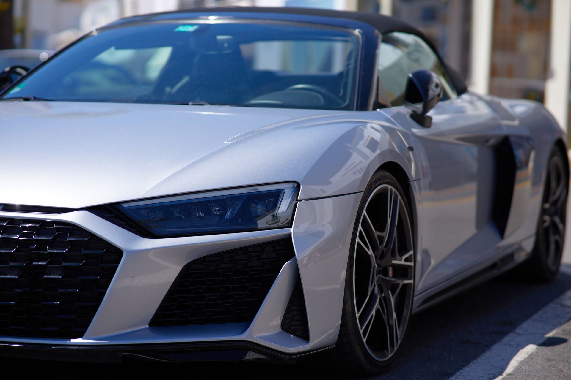 Silver sports car parked on a street, front three-quarter view, with black accents and a city background