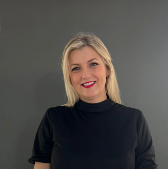 Smiling blonde woman in a black top against a gray background