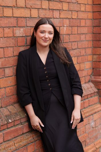 Smiling person in a black top against a dark gray background