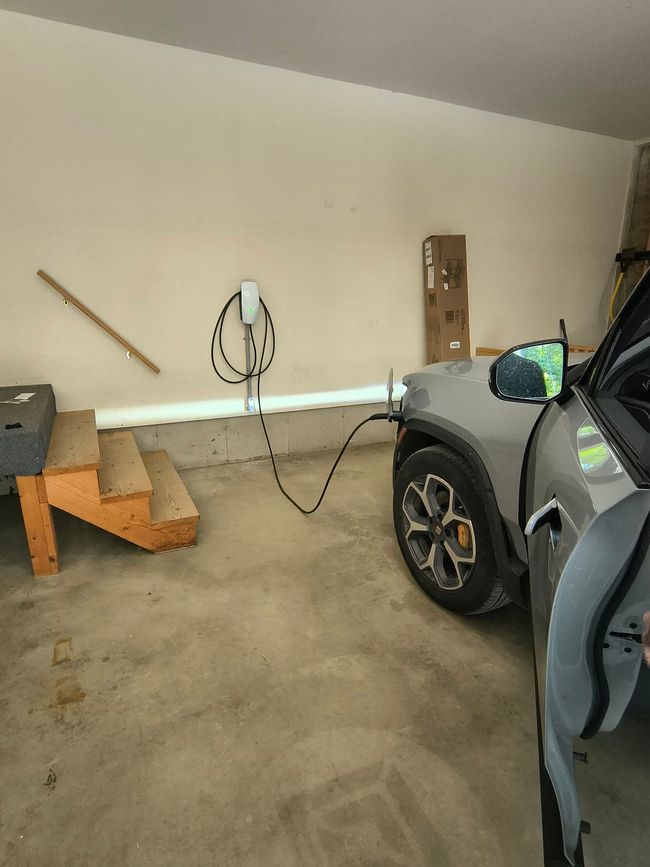 Garage with a sports car, wooden steps, a hanging cord, and a long white pipe against the wall.