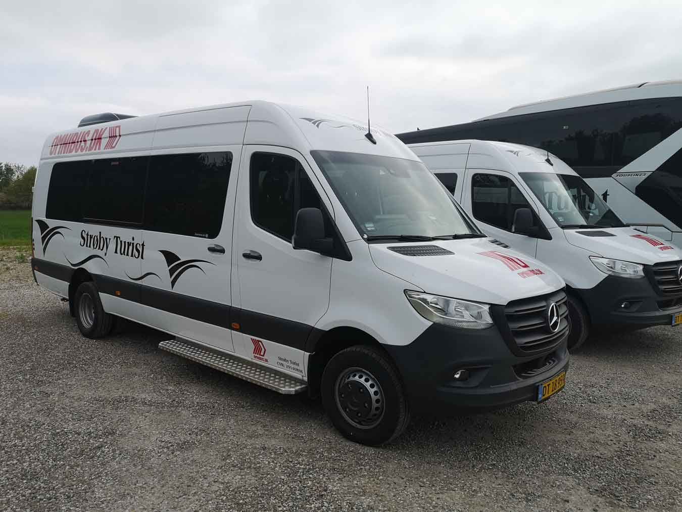 Hvid Sprinter varevogn med sort skrift og logo, parkeret på grus. En anden lignende varevogn holder bagved.