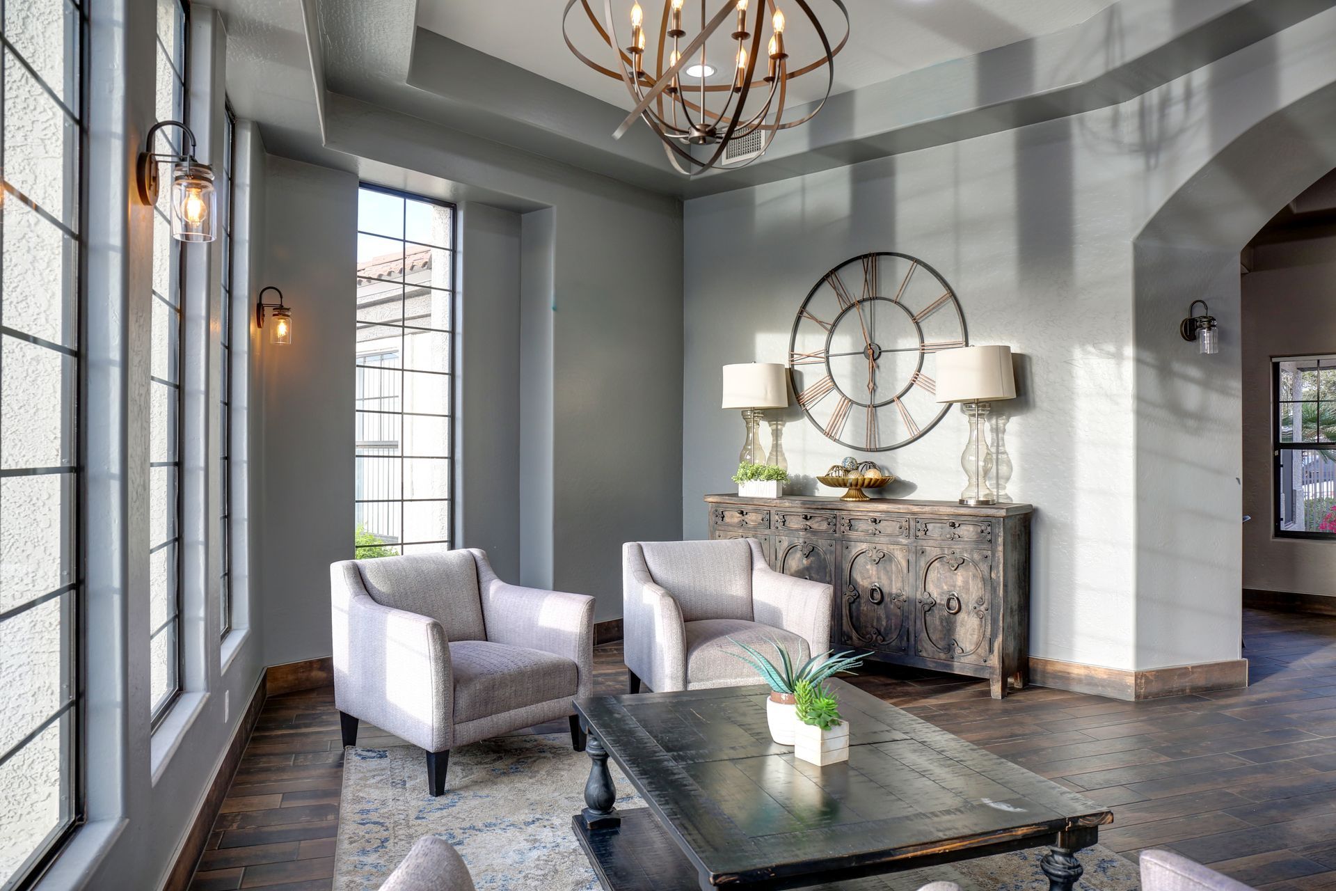 Elegant gray living room with two armchairs, fireplace, large clock, and arched doorway