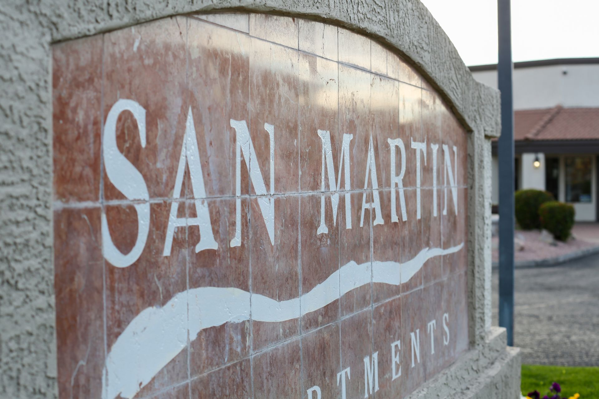 Weathered stone sign reading “San Martin” in a landscaped outdoor setting.