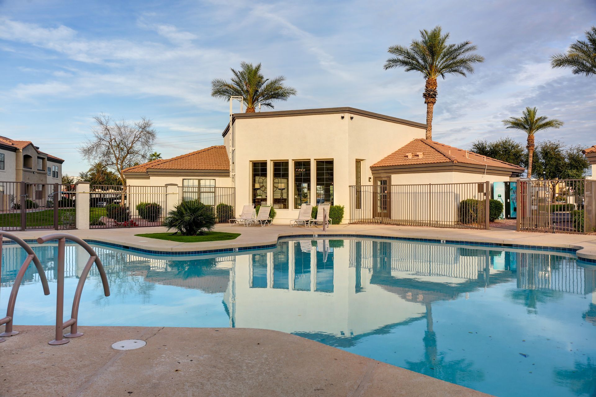 Luxury resort pool with a beige villa, palm trees, and blue water reflections
