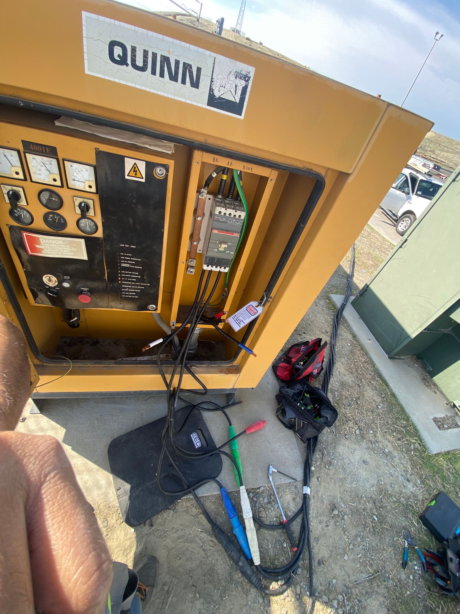 Yellow Quinn electrical cabinet with open door, wires, gauges, and tools.